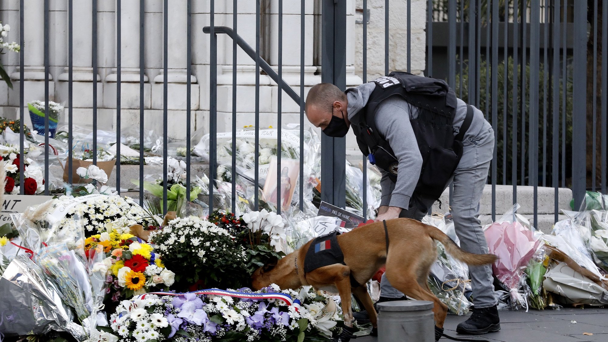 epa08791836 French police officer checks with his dog the flowers in front the Notre Dame Basilica before the first mass after the Knife attack in Nice, France, 01 November 2020. Three people have died in a terror attack. The attack comes less than a month after the beheading of a French middle school teacher in Paris on 16 October.  EPA/SEBASTIEN NOGIER