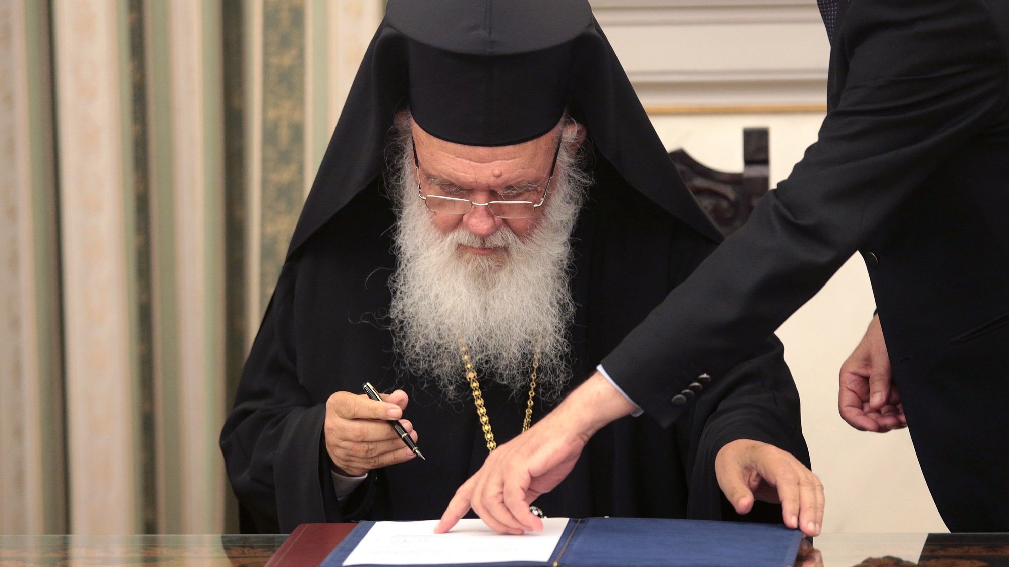 epa07703346 Greek Archbishop Ieronymos II signs documents following the swearing-in ceremony of New Democracy President Kyriakos Mitsotakis (not pictured) at the presidential palace in Athens, Greece, 08 July 2019. The center-right New Democracy party won general elections in Greece on 07 July and will form a majority government. A total of six parties will enter parliament based on the results. Voter participation reached 57.92 percent.  EPA/PANTELIS SAITAS