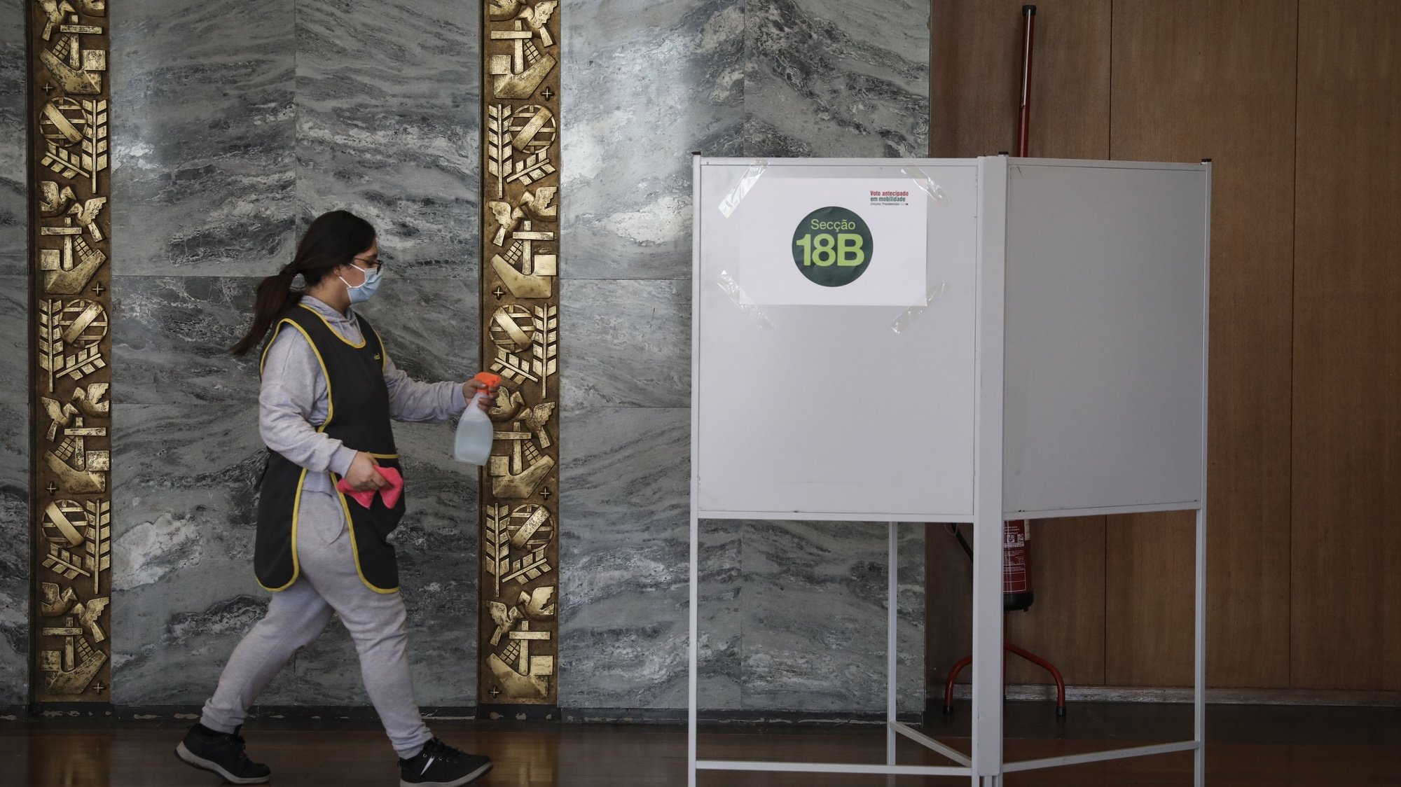Uma funcionaria da limpeza momentos andes de desinfetar a urna, no dia de voto antecipado nas Eleições Presidenciais de 2021, na Cidade Universitária, em Lisboa, 17 de Janeiro de 2021. RODRIGO ANTUNES/LUSA