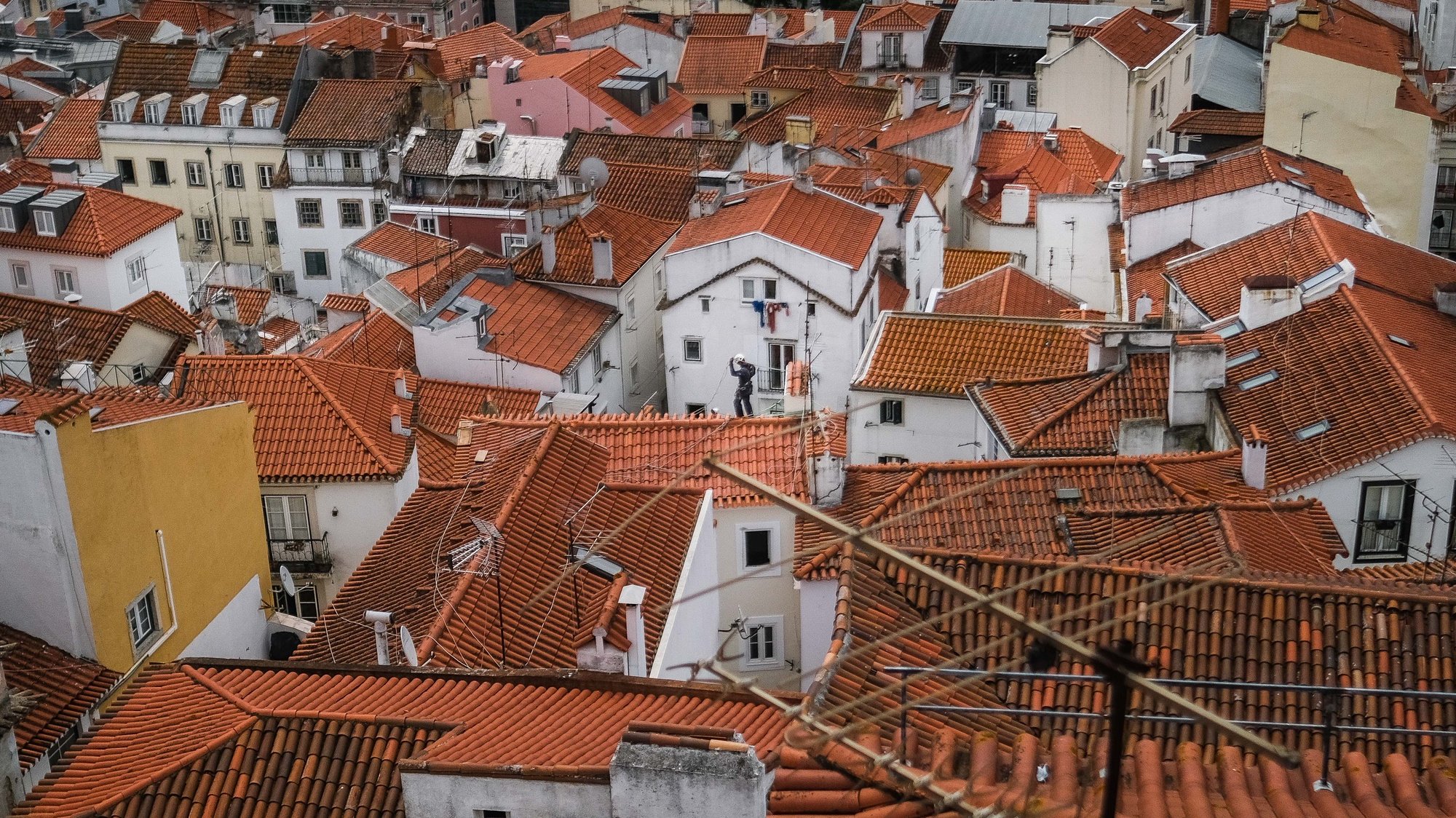 Um trabalhador nos telhados de Alfama, em Lisboa, 18 de junho de 2021. O Governo decidiu proibir as deslocações de e para a Área Metropolitana de Lisboa (AML) no fim de semana devido à subida dos casos de covid-19 neste território. MÁRIO CRUZ/LUSA