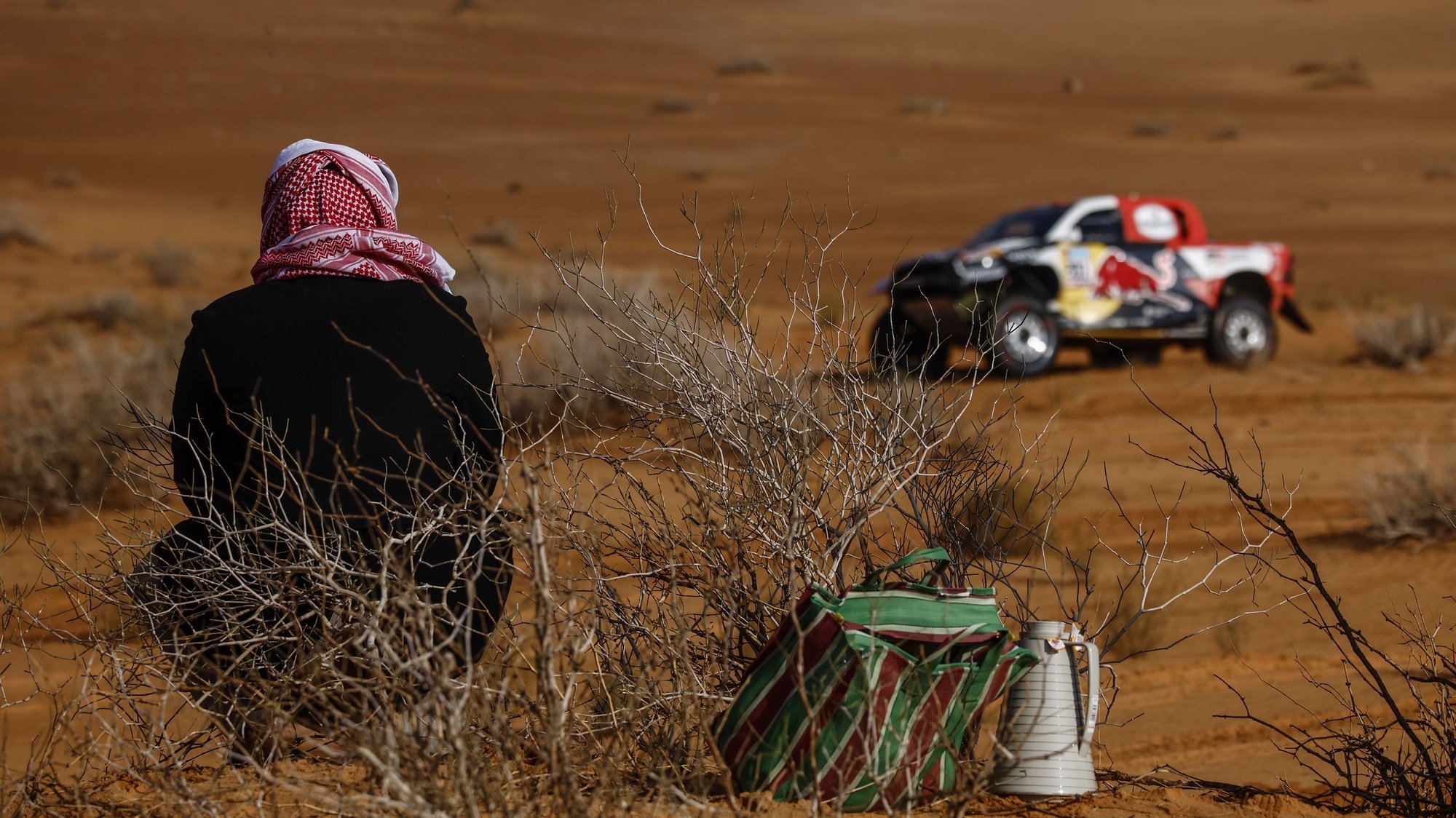 epa09663361 A Saudi spectator looks at Qatari driver Al-Attiya Nasser and French copilot Matthieu Baumel of Toyota Gazoo Racing team in action during stage 1B of the Rally Dakar 2022 between Ha&#039;il and Jeddah, Saudi Arabia, 02 January 2022.  EPA/YOAN VALAT