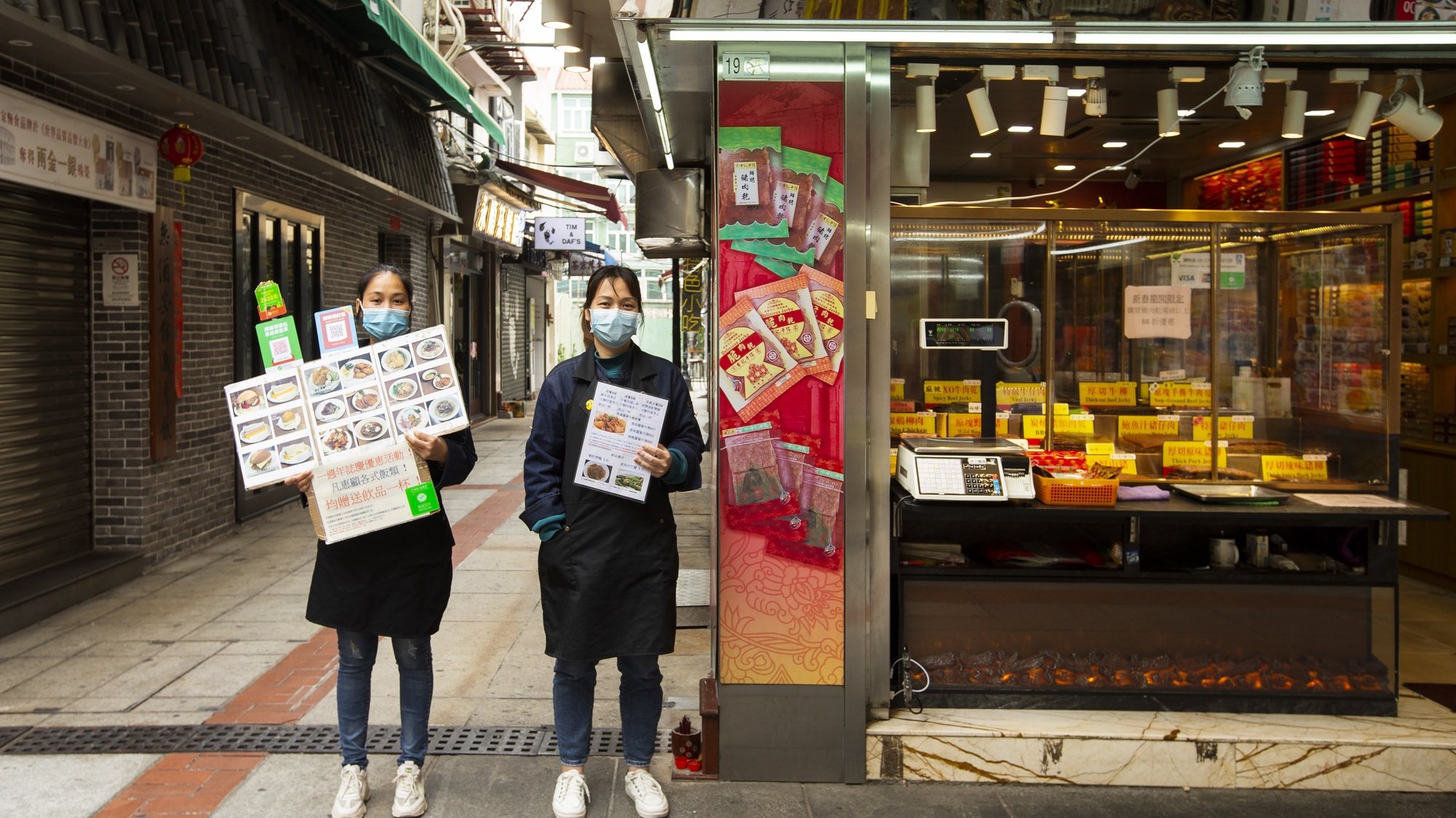 Duas mulheres promovem os seus produtos culinários numa rua vazia em Macau, na China