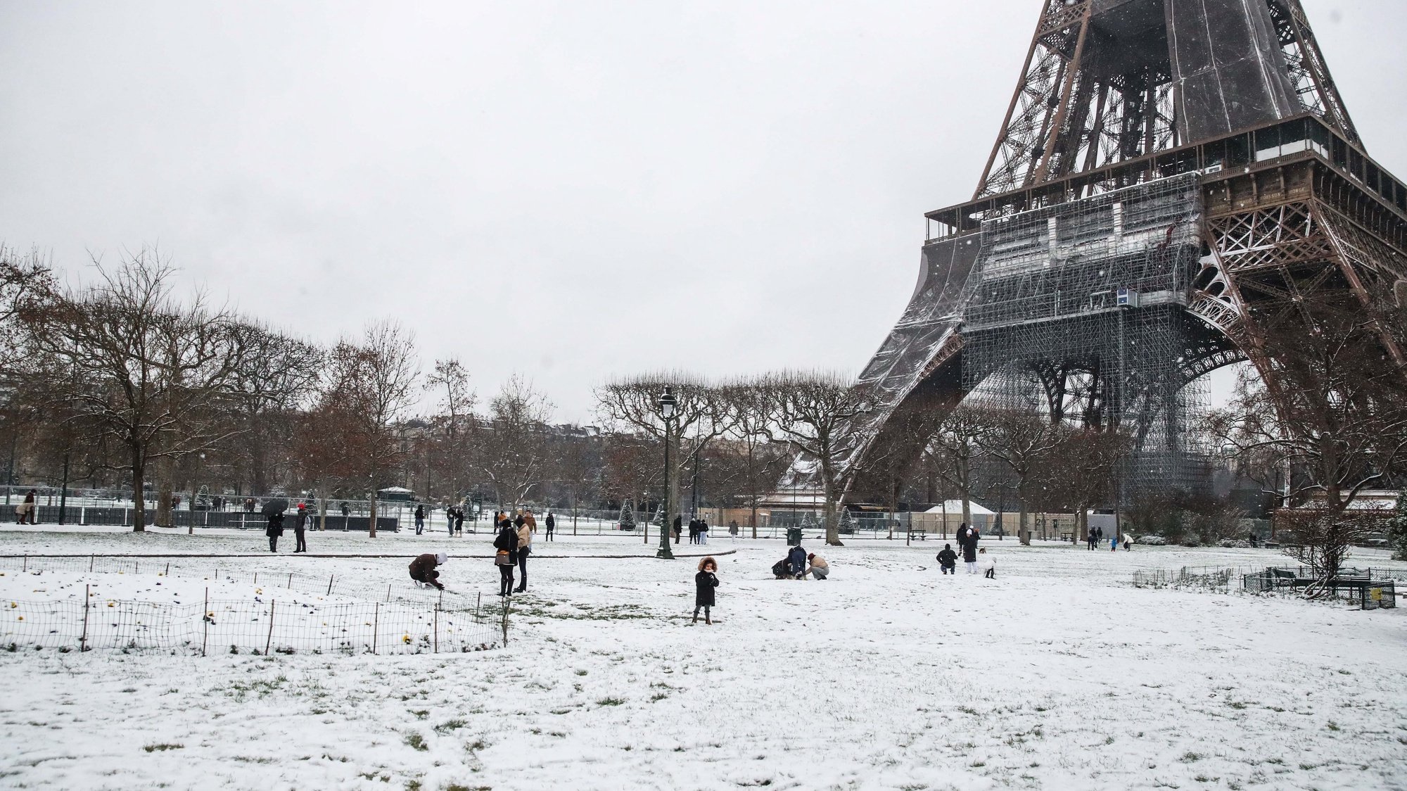 epa08941966 People play in the snow next to the Eifel Tower during snowfall in Champ de Mars, in Paris, France, 16 January 2021.  EPA/MOHAMMED BADRA