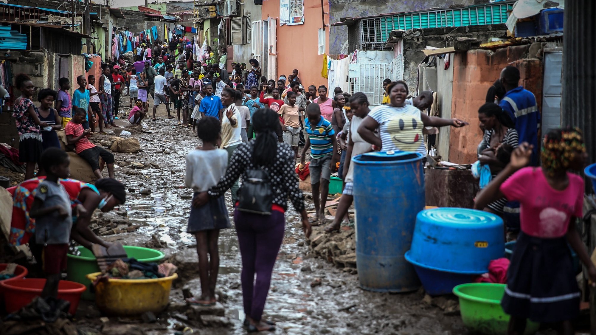epa09147887 People on a muddy street after heavy rain that fell Monday night in Encide neighborhood, in the Sambizanga district, on the outskirts of Luanda, Angola, 20 April 2021. The torrential rains that hit Luanda on 19 April killed 14 people and left 8,000 displaced, with 16 houses collapsed, 15 trees fell, and a bridge was destroyed, among other damages yet to be calculated.  EPA/AMPE ROGERIO