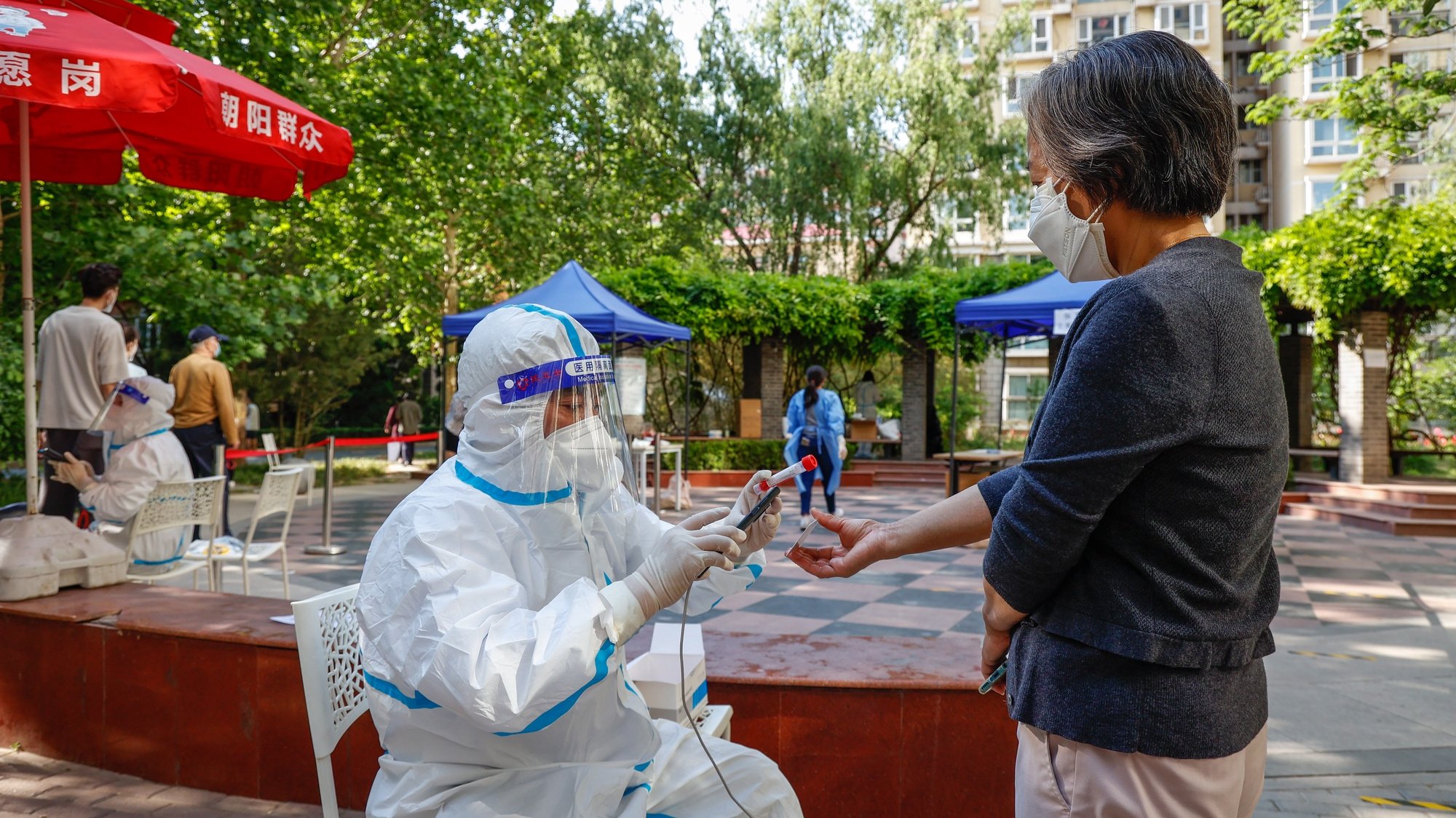 epa09950453 A health worker in protective suit takes a picture of a woman&#039;s ID at a COVID-19 test site in Beijing, China, 16 May 2022. Beijing continues its mass testing as part of its effort to curb the spread of COVID-19 in the city while authorities in Shanghai announced a relaxed lockdown starting on 01 June 2022. China&#039;s strict &#039;dynamic zero-COVID&#039; strategy has dragged its economy into the lowest level of consumption and industrial production since early 2020 as authorities have imposed partial and full lockdowns in different cities across the country.  EPA/MARK R. CRISTINO