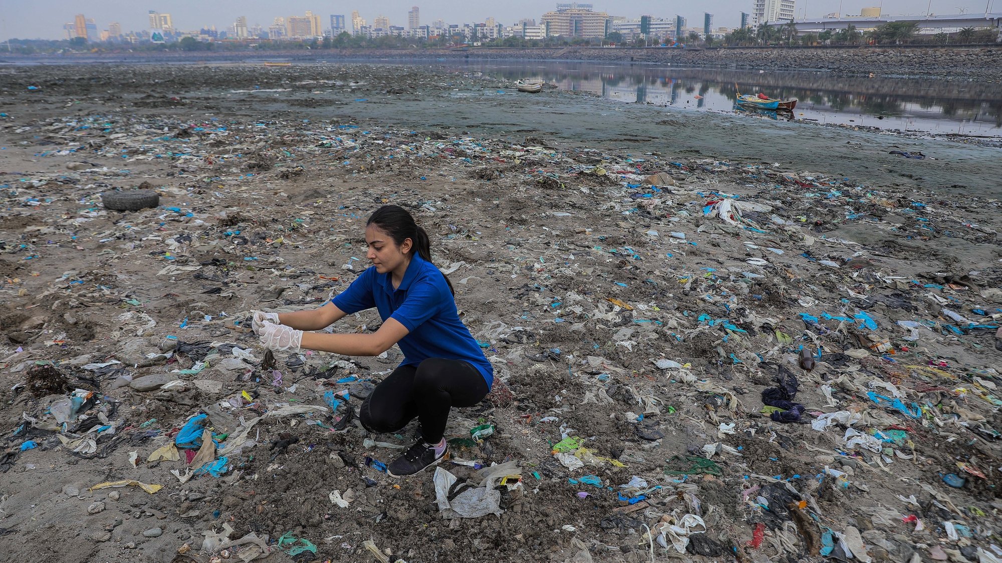 epa09901966 A volunteer picks up plastic waste and other forms of litter during a beach clean-up drive on the occasion of Earth Day 2022, at the seashore of Mahim beach, in Mumbai, India, 22 April 2022. Earth Day is celebrated every year on 22 April to raise awareness on environmental protection.  EPA/DIVYAKANT SOLANKI