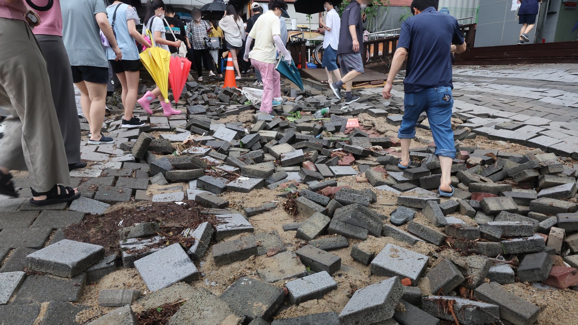 epa10112049 People cautiously walk on a damaged road near a subway station in Seoul, South Korea, 09 August 2022. The heaviest rainfall in 80 years, over 100 millimeters per hour, battered Seoul and surrounding areas the previous night.  EPA/YONHAP SOUTH KOREA OUT