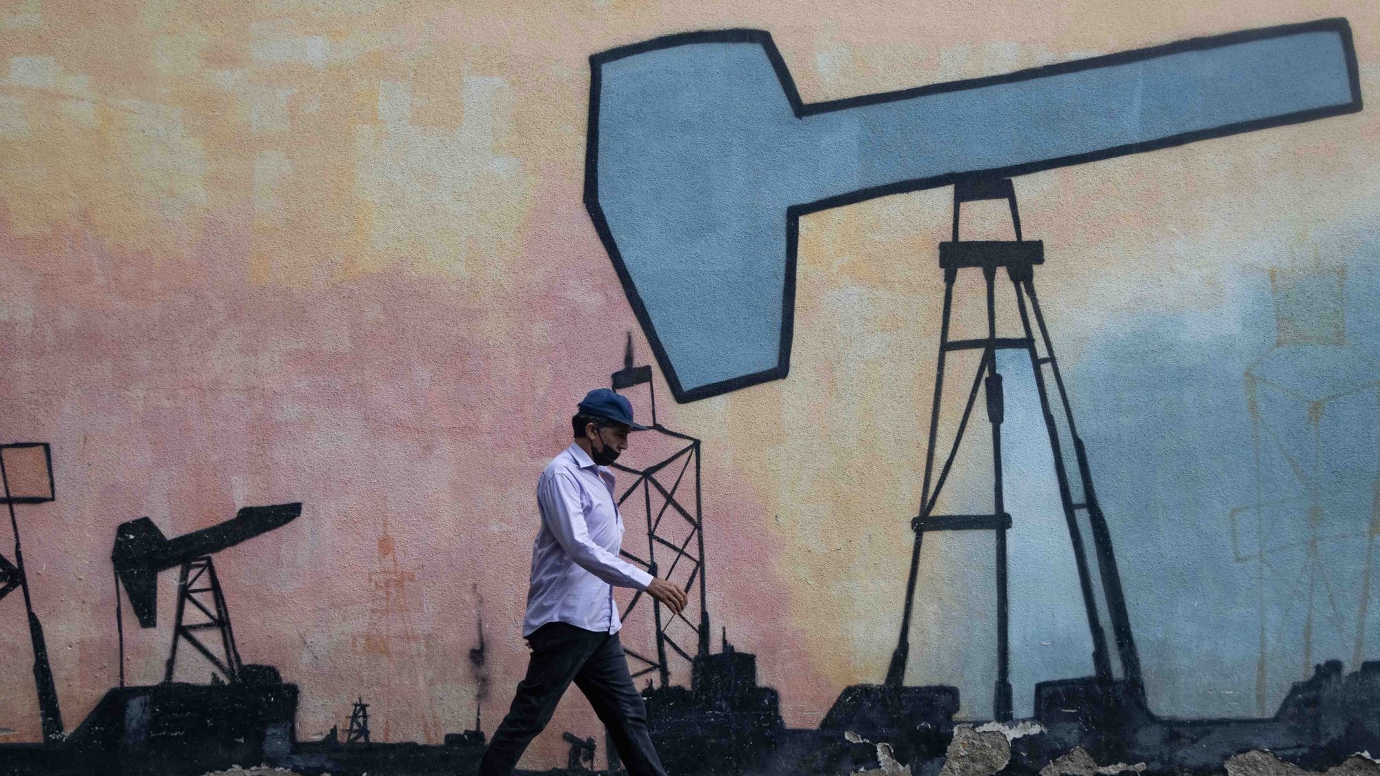 epa09902970 A man walks in front of a mural showing the oil extraction process, in front of a headquarters of the state-owned Petroleos de Venezuela S.A (PDVSA), in Caracas, Venezuela, 21 April 2022 (issued 22 April 2022). The recovery of Venezuela&#039;s oil production, which went from 3.2 million barrels per day (bpd) in 1998 to now no more than one million, is one of the main goals of President Nicolas Maduro in the midst of the global energy crisis, but, in the opinion of experts, difficult to achieve without a resolution of the internal political conflict and with the sanctions still in force.  EPA/Ronald Pena