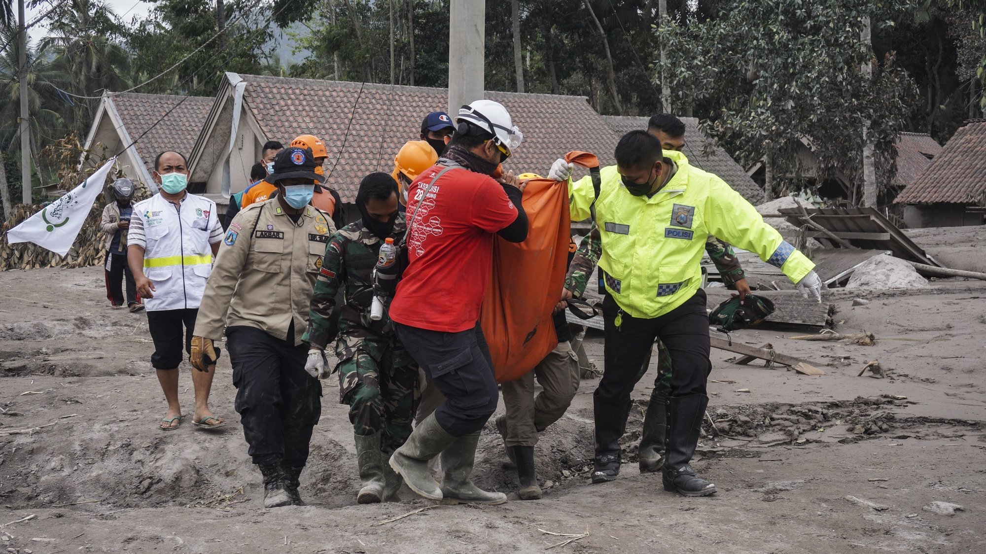 epa09625052 Rescuers carry the body of a victim at an area affected by the eruption of Mount Semeru in Lumajang, East Java, Indonesia, 06 December 2021. The volcano erupted on 04 December, killing at least 14 people and leaving dozens of others injured.  EPA/AMMAR