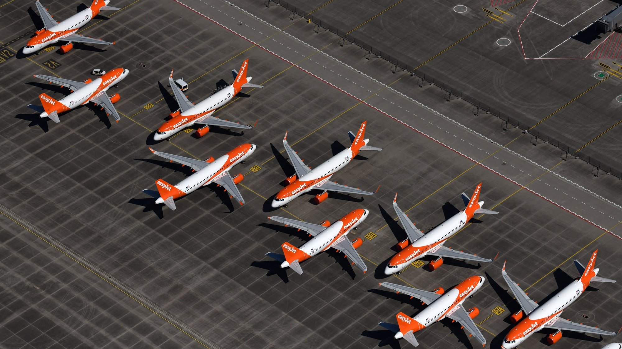 epa08388424 An aerial view shows air planes of EasyJet sitting on the tarmac at the Berlin Brandenburg International Airport in Schoenefeld, Germany, 23 April 2020 (issued 28 April 2020). Due to personal contact restrictions, which were implemented as part of measures to stem the spread of the SARS-CoV-2 coronavirus, gatherings of more than two persons are forbidden in Germany.  EPA/OLIVER LANG