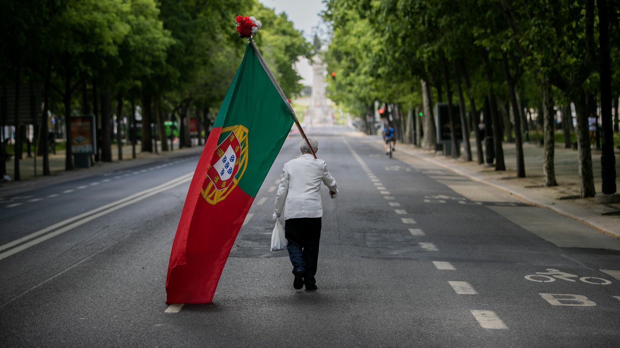 Um homem com uma bandeira de Portugal sobe a Avenida da Liberdade em Lisboa, por volta das 15 horas, altura em que anualmente se realiza um desfile comemorativo do 25 de abril de 1974 e que, devido à pandemia da covid-19, não pode ter lugar, em Lisboa, 25 de abril de 2020. Os 46 anos do 25 de Abril estão a ser hoje celebrados de forma diferente em Portugal, com uma sessão solene reduzida no parlamento, sem o tradicional desfile e com um apelo para que os portugueses cantem a ‘Grândola&#039; à janela. JOSÉ SENA GOULÃO/LUSA