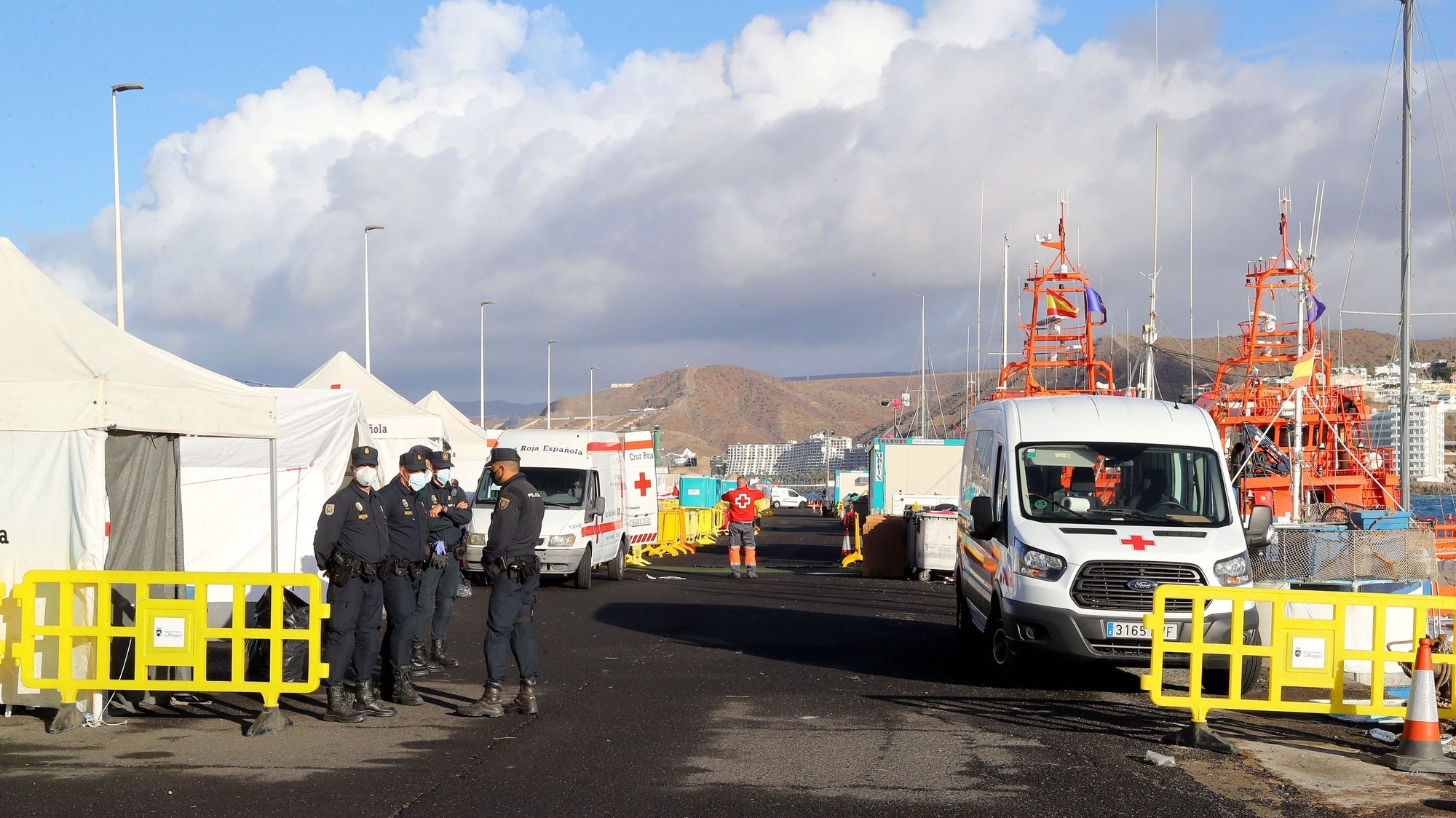 epa08852974 Police officers stand guard as work begins on dismantling the refugee camp in Arguineguin port in Gran Canarias, Spain, 30 November 2020. The migrant camp at its peak housed 2,600 people.  EPA/Elvira Urquijo A.