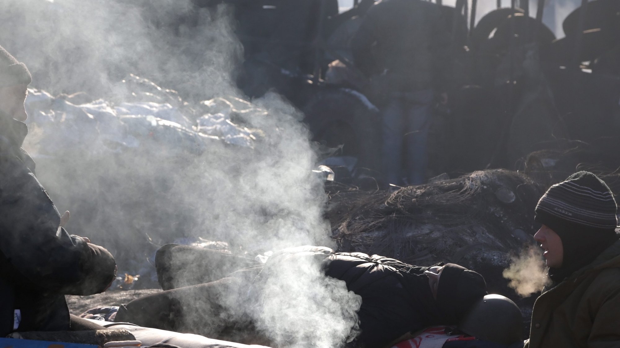 epa04054428 A protester takes a nap near a fire at a barricade during the continuing protests in Kiev, Ukraine, 04 February 2014. Violent street riots have been ongoing in Kiev and other cities in Ukrain since late November 2013, when President Viktor Yanukovych reneged on a trade agreement with EU and opted for closer ties with Moscow instead. Protesters in Ukraine continued to occupy government buildings on 30 January, hours after parliament approved an amnesty for the hundreds of people jailed during weeks of demonstrations on the condition that the buildings are vacated and the protests end.  EPA/MAXIM SHIPENKOV