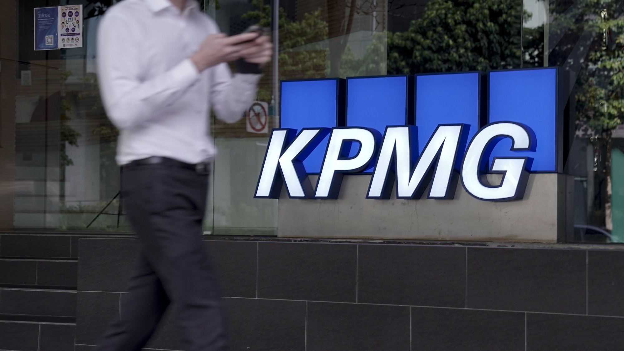 epa08777182 A man walks past the logo of auditing firm KPMG in the financial district in Singapore, 27 October 2020. The fallout of the global Covid-19 coronavirus pandemic has had a range of effects across workers from different sectors of the economy. As businesses gradually open up, economists are describing a &#039;K-shaped&#039; recovery caused by lower wage workers affected by health and safety regulations, while white collar workers remain largely unaffected due to the advent of telecommuting and work from home arrangements.  EPA/WALLACE WOON