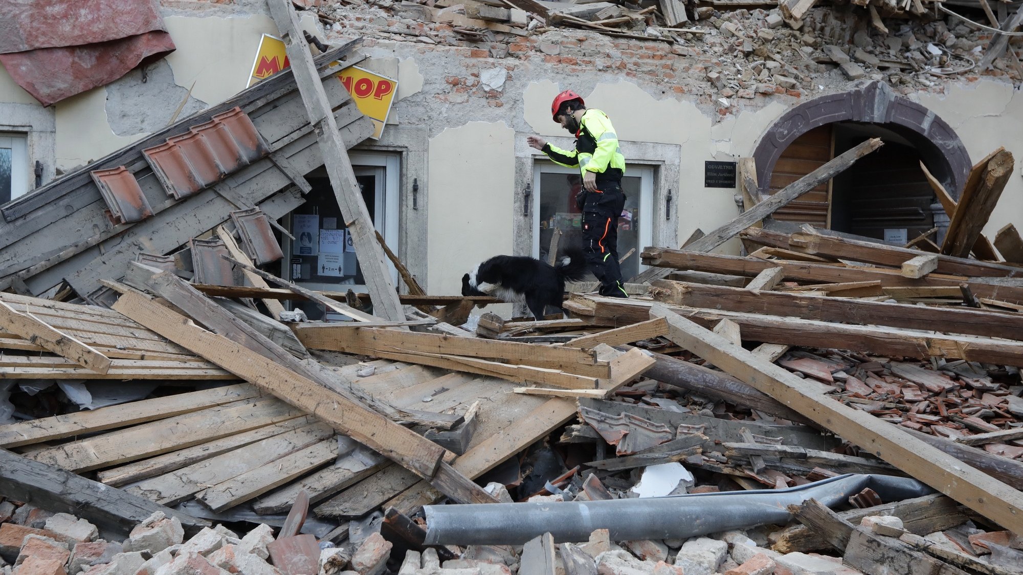 epa08909778 A rescue worker and his dog inspect buildings damaged in an earthquake in Petrinja, Croatia, 29 December 2020. A 6.4 magnitude earthquake struck around 3km west south west of the town with reports of many injuries and at least one death.  EPA/ANTONIO BAT