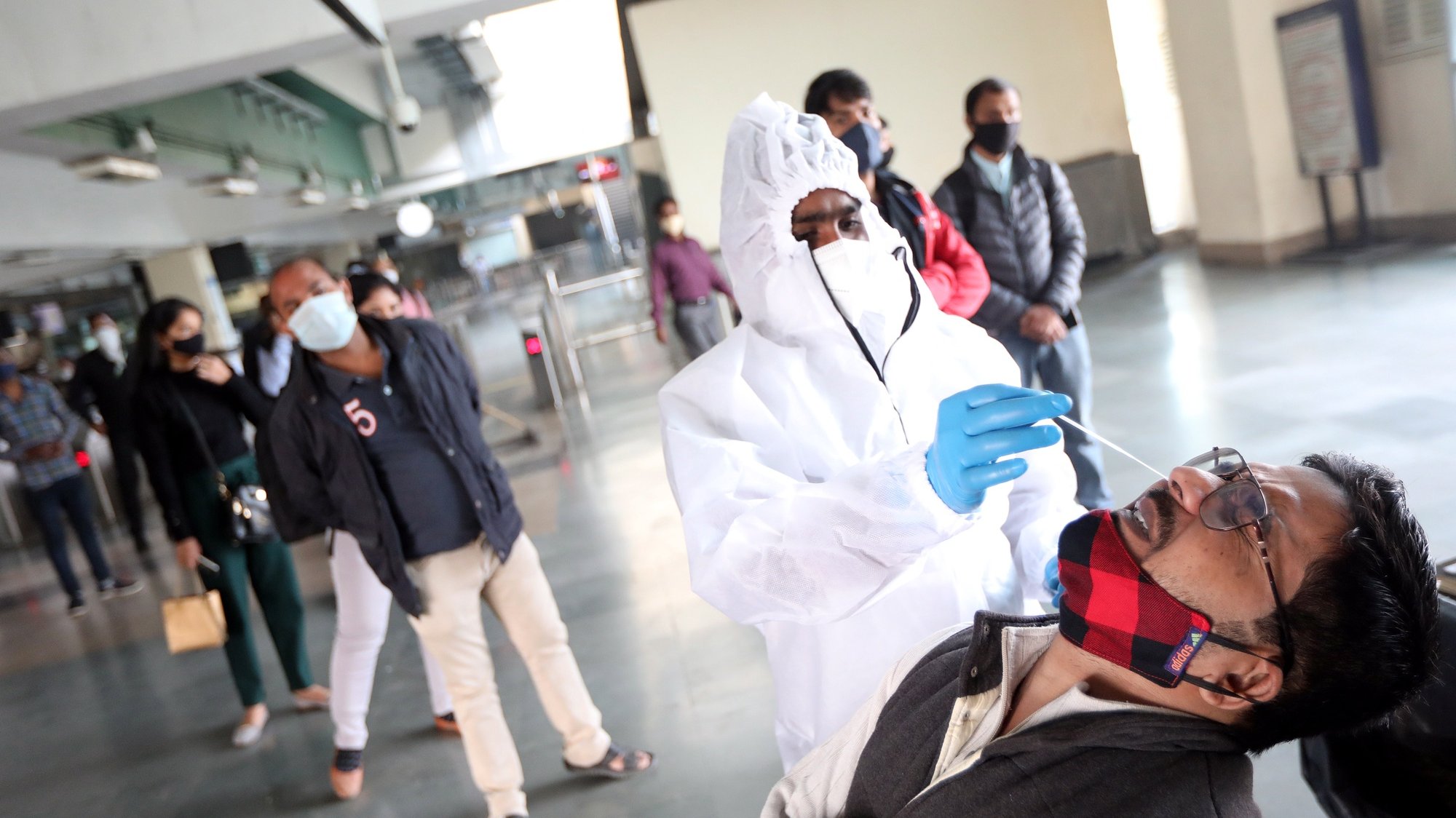epa08838677 Indian medical personnel collect swab samples for a coronavirus COVID-19 Rapid Antigen detection tests from a person at a metro station near New Delhi, India, 24 November 2020. A special drive started for random COVID-19 testing at the Delhi borders, bust stands, Metro stations after Delhi recorded over 6,000 new COVID-19 cases over the last 24 hours. The Delhi government is calling this latest surge the third wave of coronavirus as India continues to be the second worst-hit country by the spread of the COVID-19 disease, only behind the United States.  EPA/HARISH TYAGI