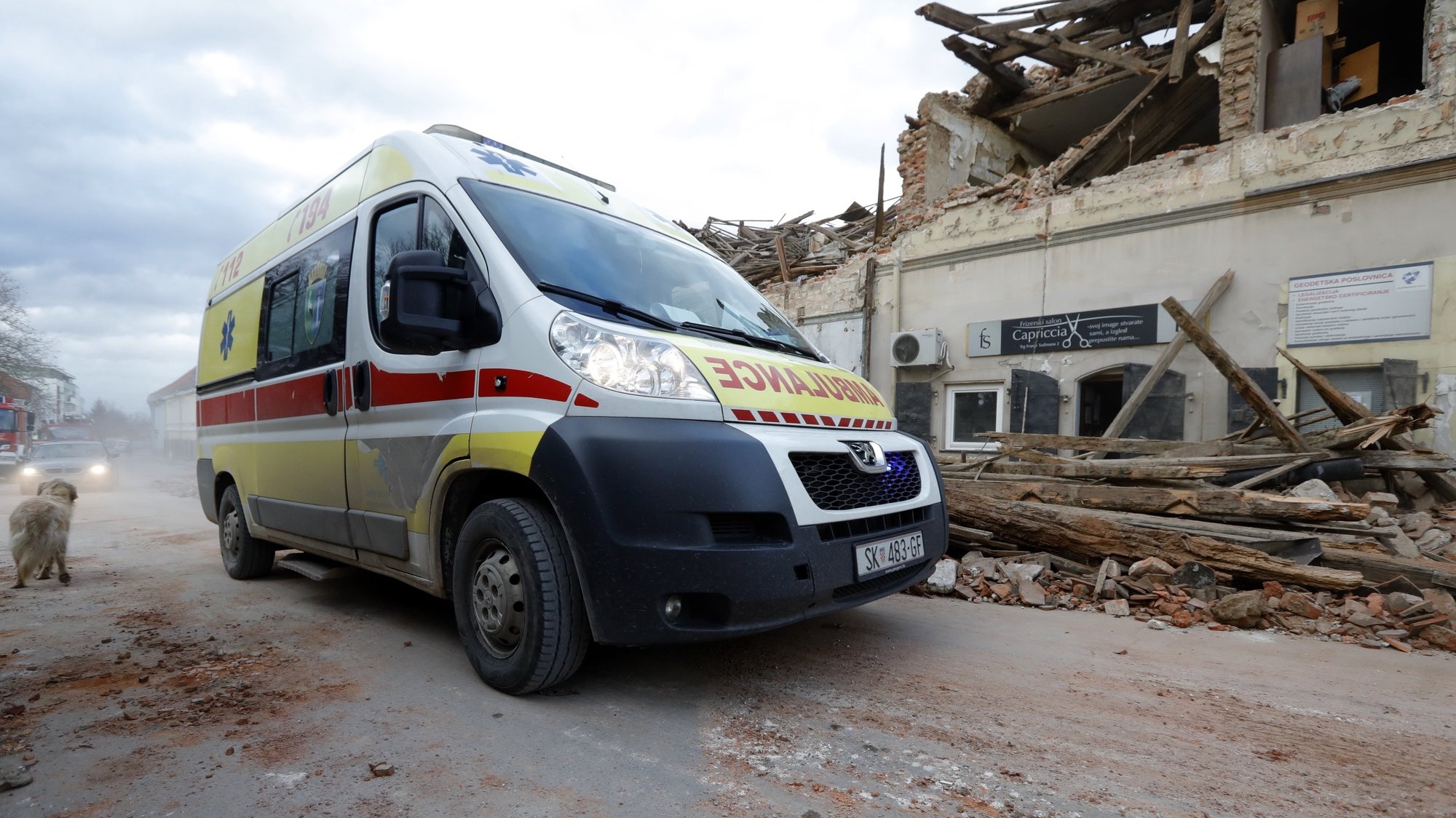epa08909780 An ambulance drives past buildings damaged in an earthquake in Petrinja, Croatia, 29 December 2020. A 6.4 magnitude earthquake struck around 3km west south west of the town with reports of many injuries and at least one death.  EPA/ANTONIO BAT