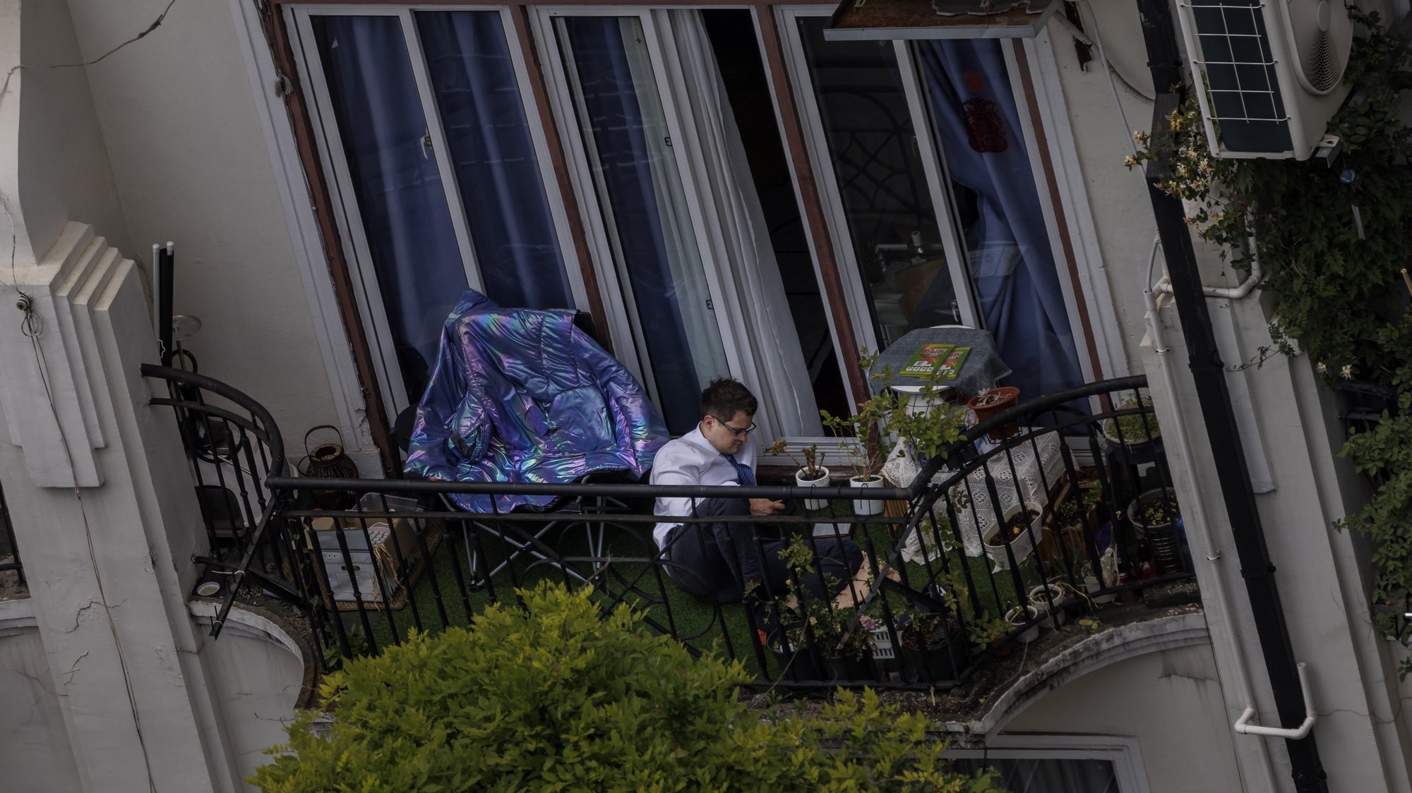 epa09952127 A man sits on his balcony at residential compound in quarantine, amid the ongoing Covid-19 lockdown in Shanghai, China, 17 May 2022. Shanghai city reported one coronavirus-related death, 77 locally transmitted cases, and 746 local asymptomatic infections, according to the Shanghai Health Commission on 17 May 2022. Shanghai reached the &#039;Zero COVID&#039; status, with no new COVID-19 cases outside of quarantine zones. Shanghai Vice Mayor Zong Ming announced a day earlier that life and business will return to normal between 01 June and mid-to-late next month as the city&#039;s pandemic has been put under control, and the city is now following a three-phase opening up plan.  EPA/ALEX PLAVEVSKI