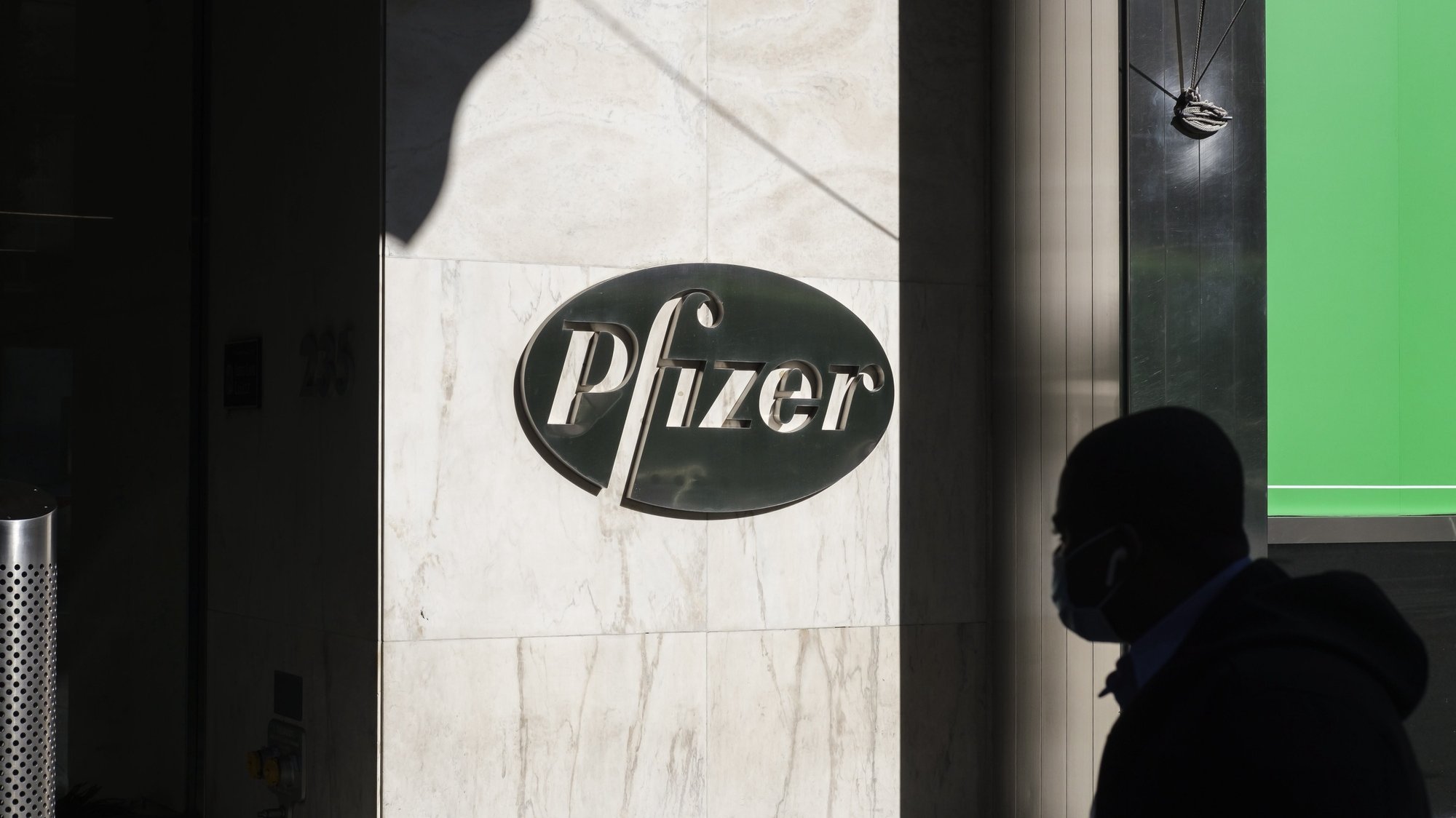 epa08810220 A person walks past the headquarters of the pharmaceutical company Pfizer in New York, New York, USA, 09 November 2020. Pfizer announced earlier on the same day that a coronavirus vaccine it was developing with the German drugmaker BioNTech was showing a 90 percent effectiveness in preventing COVID-19 earlier trials.  EPA/JUSTIN LANE