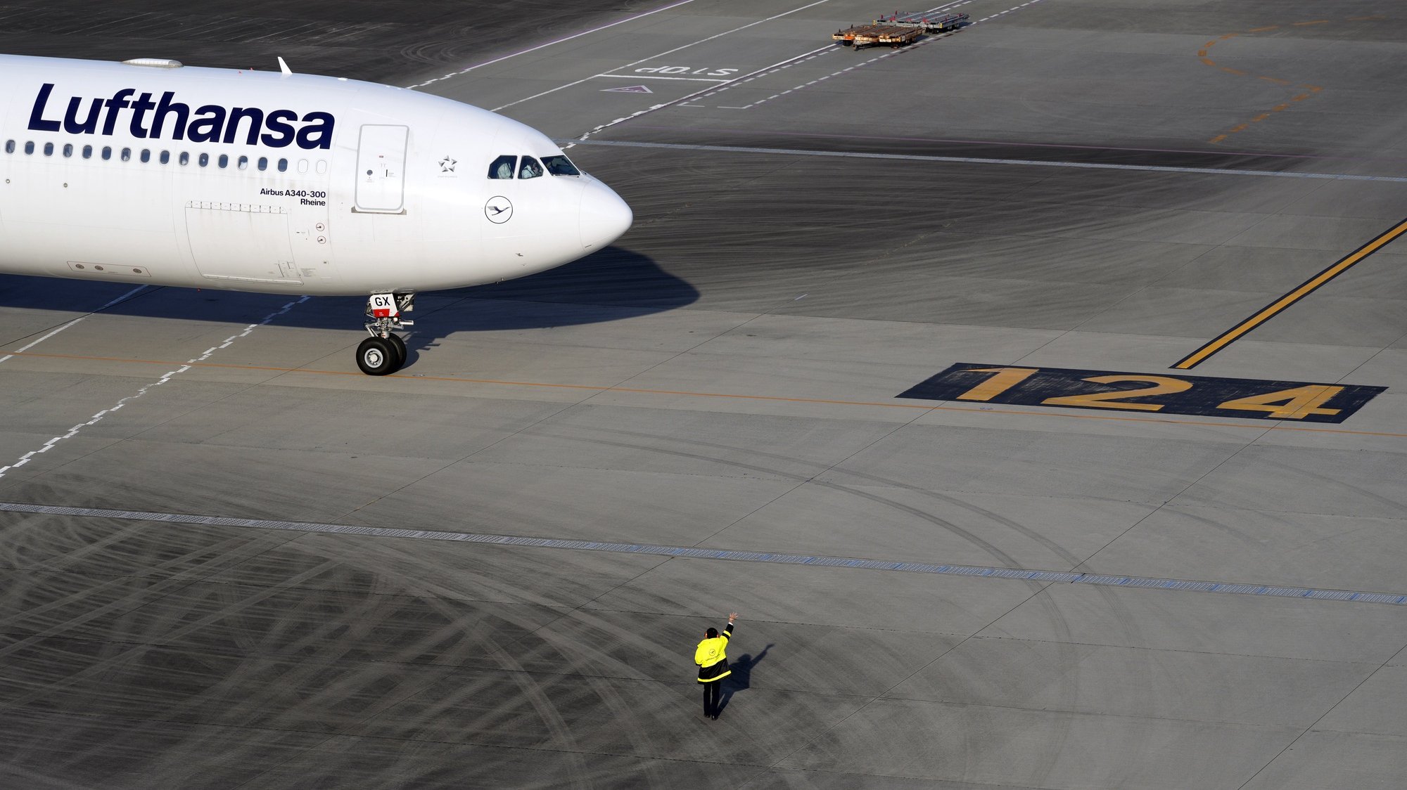 epaselect epa09610517 A ground staff member waves to a departing Lufthansa aircraft at Haneda International Airport in Tokyo, Japan, 29 November 2021. In response to the emergence of the new Omicron variant of Sars-CoV-2, Japan&#039;s Prime Minister Fumio Kishida decided to ban new entry of foreigners from 30 November.  EPA/FRANCK ROBICHON