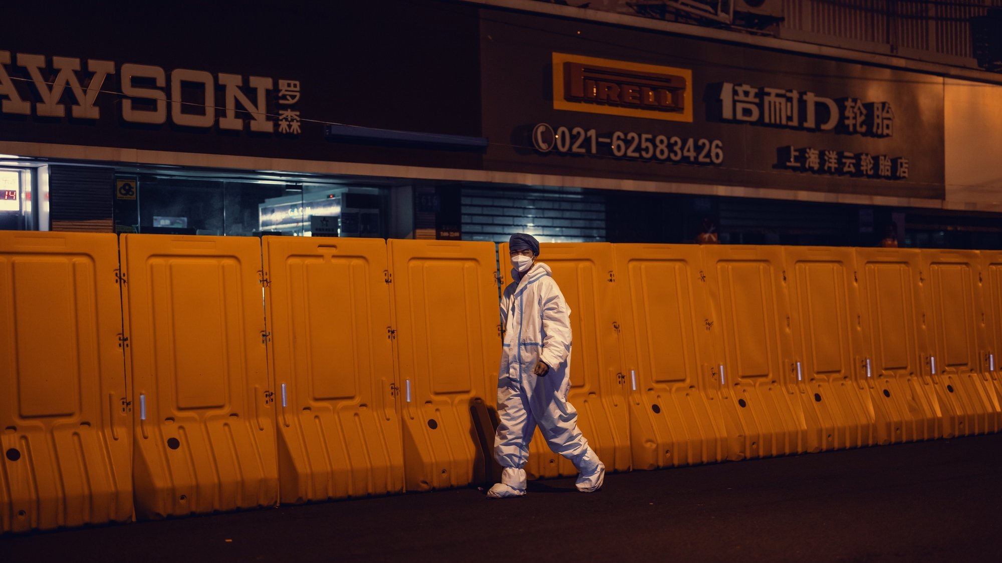 epa09977566 A man in protective gear walks in front of the quarantine barrier, amid the ongoing Covid-19 lockdown in Shanghai, China, 26 May 2022. Shanghai city reported one COVID-19 death, 48 locally transmitted cases, and 290 local asymptomatic infections, according to the Shanghai Health Commission on 26 May 2022. Grade 11 and 12 senior high school students will return to campus on 6 June, and Grade 9 on 13 June, Shanghai Education Commission reported. Students must take an antigen test before school, a PCR test before leaving, and a temperature check twice a day at school. Offline classes are optional.  EPA/ALEX PLAVEVSKI