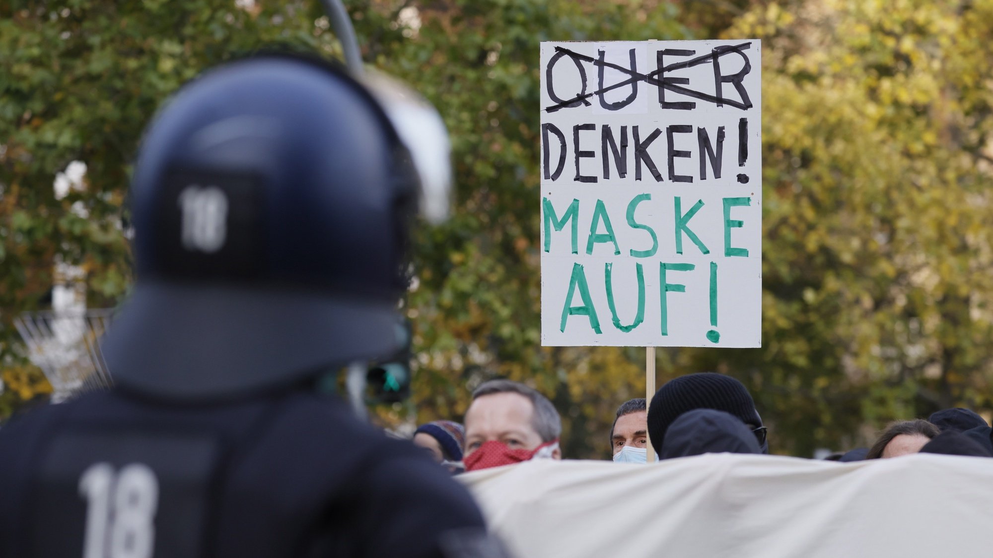 epa08820000 A left-wing protester holds a placard reading &#039;Think! Wear maska!&#039; while trying to stop a demonstration against the coronavirus restrictions in Frankfurt am Main, Germany, 14 November 2020. The protests organized by the Third Position movement &#039;Querdenken&#039; were held against government-imposed semi-lockdown measures aimed at curbing the spread of the coronavirus pandemic. Starting 02 November, all restaurants, bars, cultural venues, fitness studious, cinemas and sports halls will be forced to close for four weeks as a lockdown measure to rein in skyrocketing coronavirus infection rates.  EPA/RONALD WITTEK