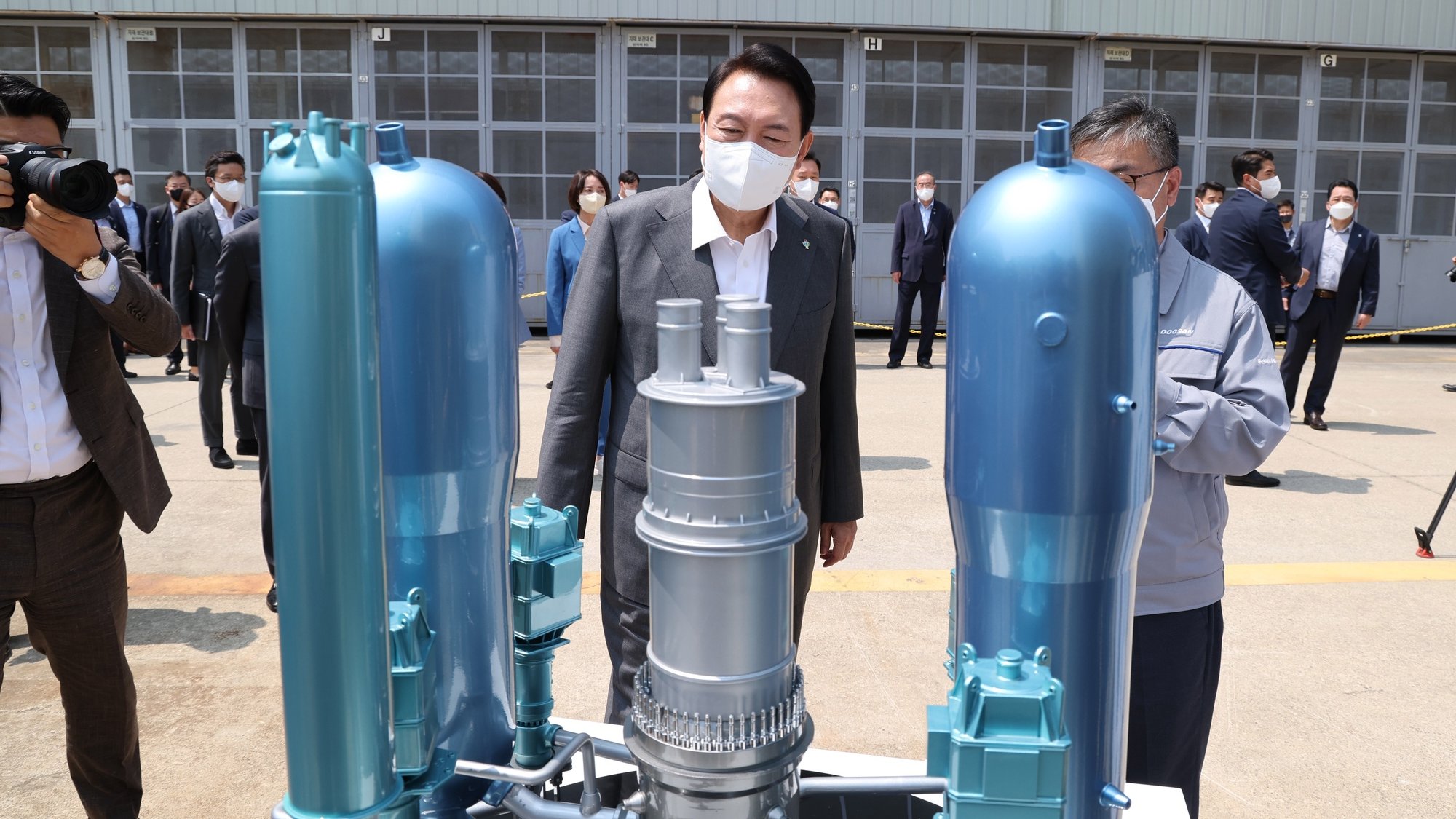 epa10027061 President Yoon Suk-yeol (C) views a miniature model of a South Korean-built APR1400 reactor as he tours a nuclear reactor factory of Doosan Enerbility in Changwon, South Korea, 22 June 2022. Yoon pledged to rebuild the nuclear power industry and support its expansion overseas, underscoring his commitment to reversing the nuclear phase-out policy of the previous administration.  EPA/YONHAP SOUTH KOREA OUT