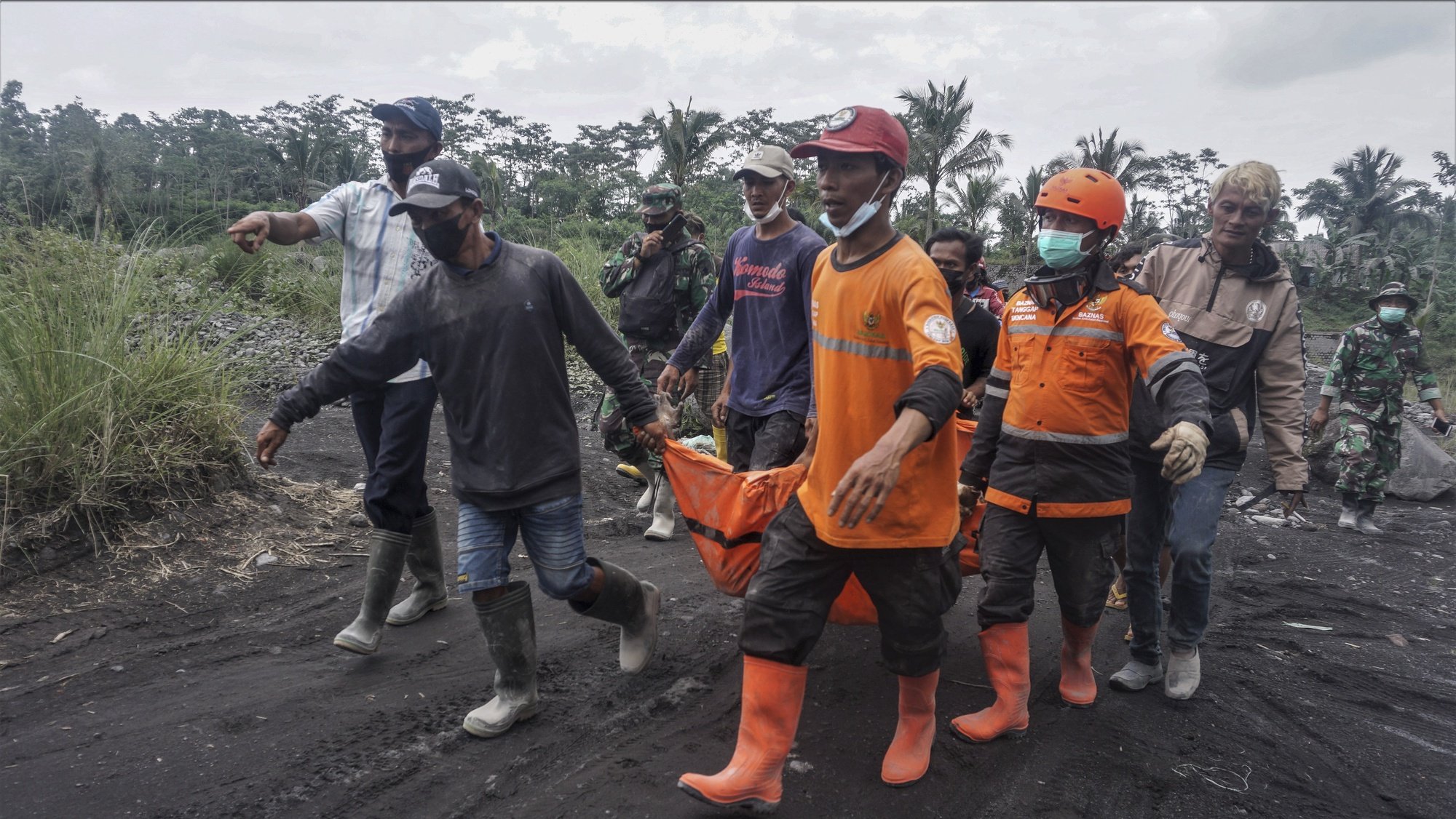 epa09622890 Rescuers carry the body of a victim of the Mount Semeru eruption in a village in Lumajang, East Java, Indonesia, 05 December 2021. The volcano erupted on 04 December leaving a number of people killed and missing.  EPA/AMMAR