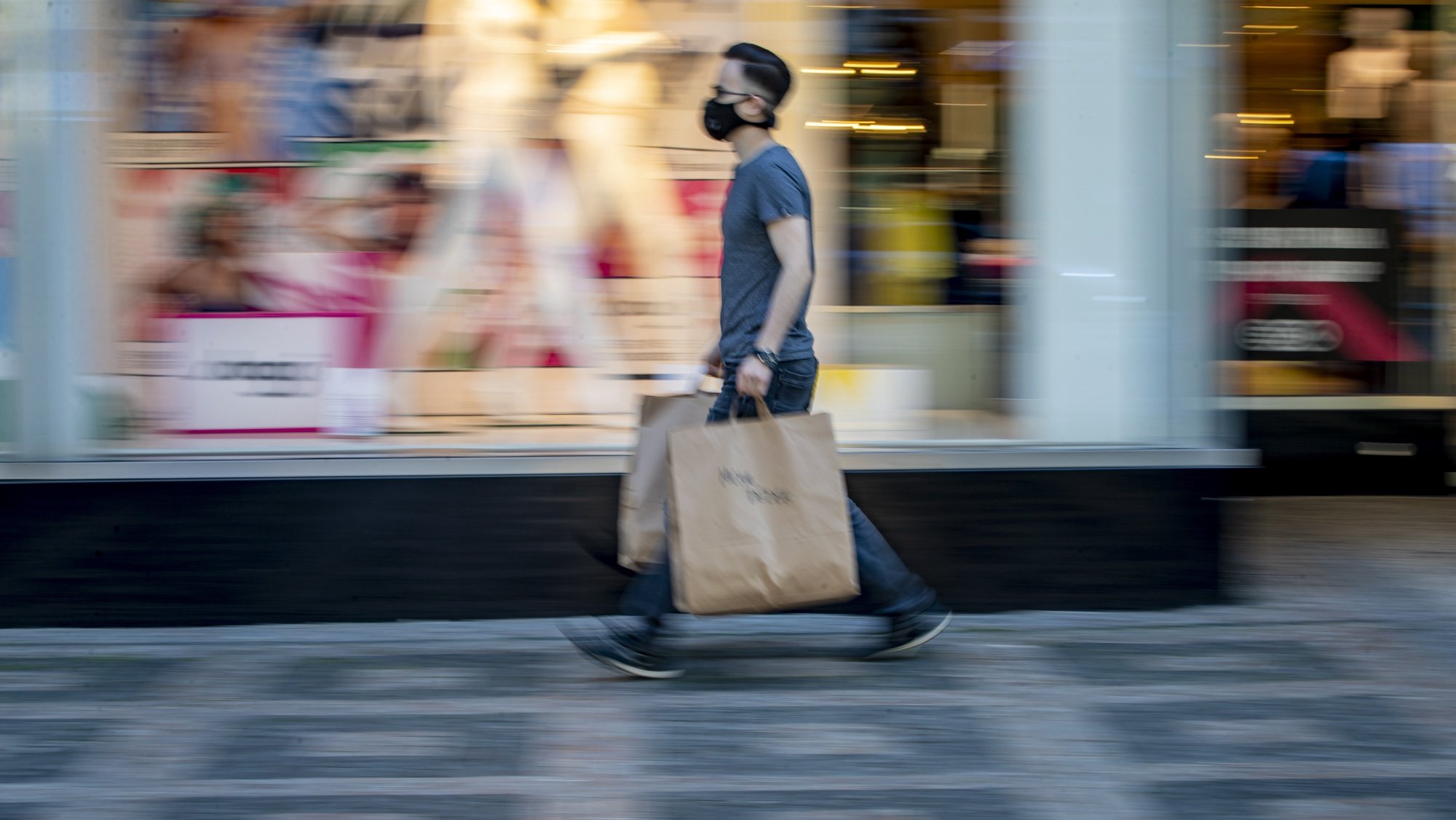 Um homem carrega sacos de compras no primeiro dia de reabertura das lojas em Praga, República Checa, 10 de maio de 2021
