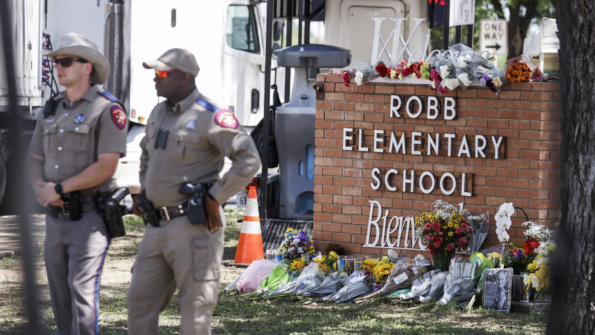 epa09976024 Texas Highway Patrol officers stand near a memorial of flowers at the scene of a mass shooting at the Robb Elementary School in Uvalde, Texas, USA, 25 May 2022. According to Texas officials, at least 19 children and two adults were killed in the shooting. The eighteen-year-old gunman was killed by responding officers.  EPA/TANNEN MAURY