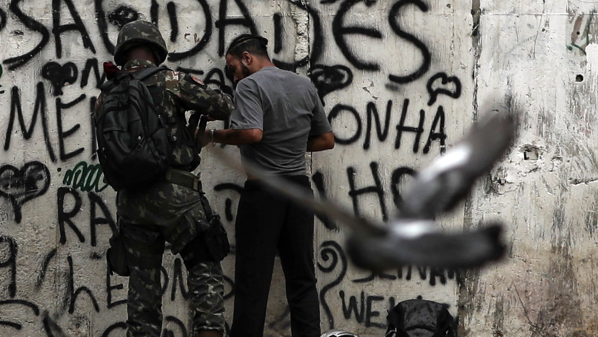 epa07035265 aA local man is searched as armed military soldiers patrol in a neighbohood in Rio de Janeiro, Brazil, 20 September 2018. Nearly 450 members of the Armed Forces participate in an operation against drug trafficking at the Jacarezinho slum in Rio de Janeiro.  EPA/ANTONIO LACERDA