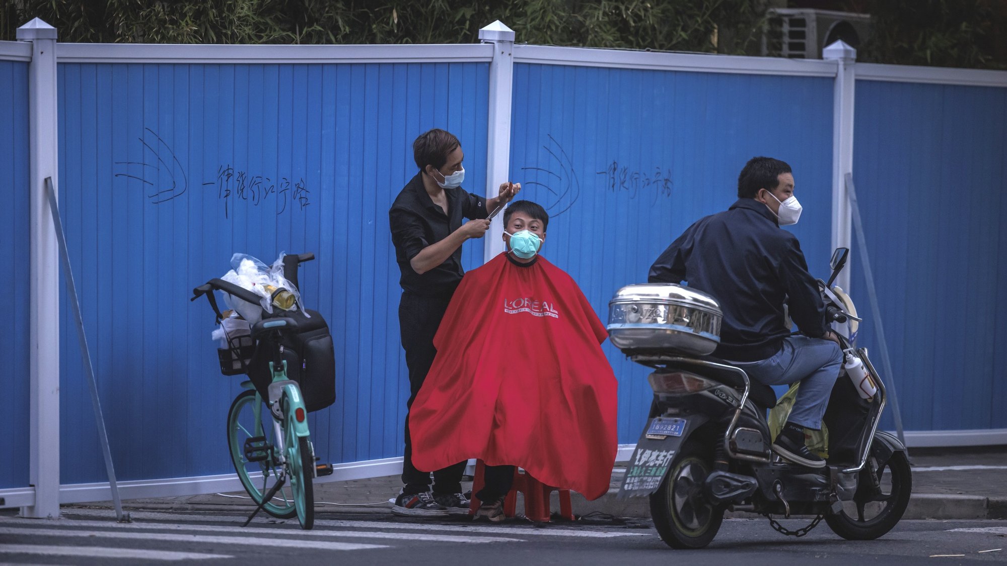 epa09935917 A man has a haircut on the street amid the ongoing Covid-19 lockdown in Shanghai, China, 09 May 2022. Shanghai on 09 May reported a drop in Covid-19 cases, while the city has been under strict lockdown amid China&#039;s zero-Covid policy for six consecutive weeks.  EPA/ALEX PLAVEVSKI