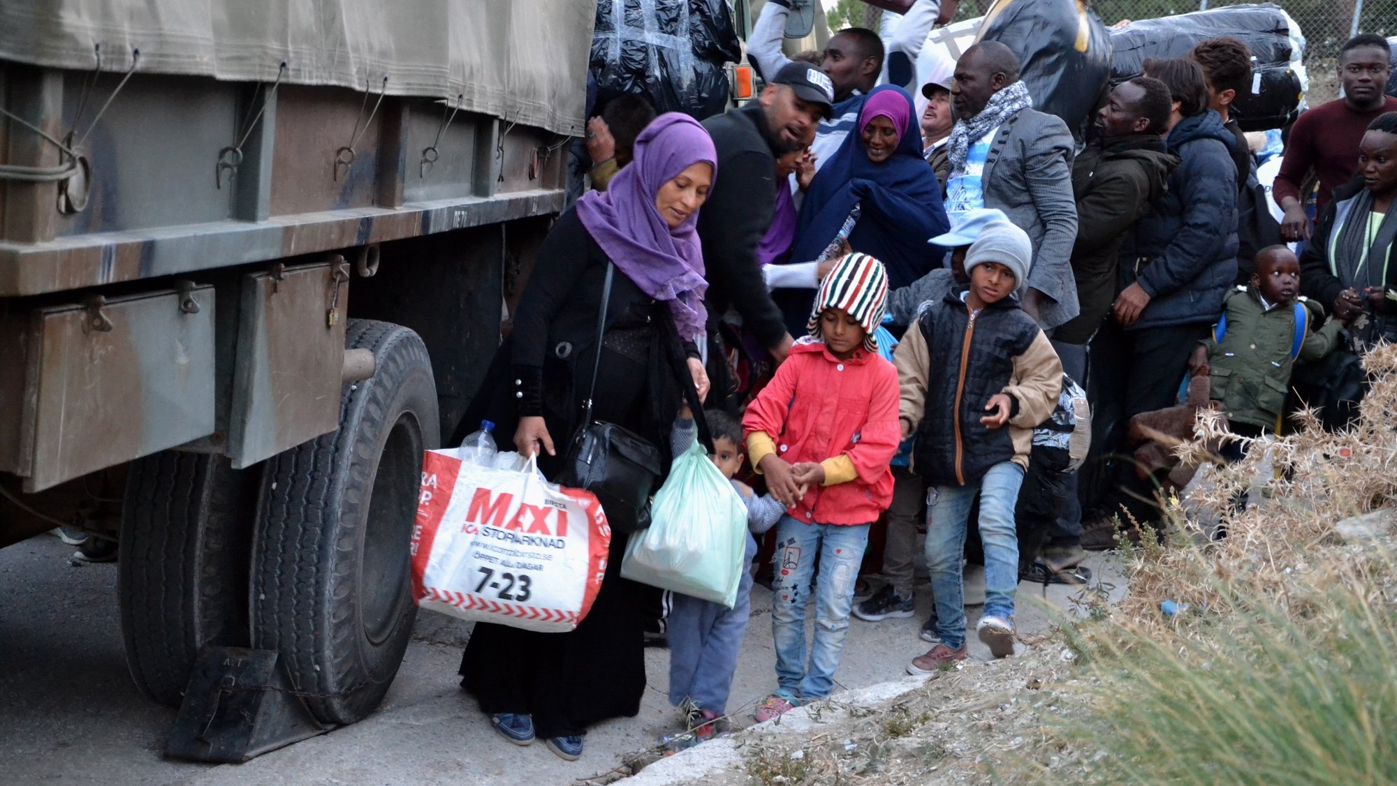 epa07965458 Refugees board a military vehicle outside the hotspot in Moria, Lesvos island, Greece, 01 November 2019, to be transferred by navy ships to the mainland Greece. Over 1,000 asylum applicants will be transferred from NE Aegean islands to the mainland in the next three days. According to sources speaking to Athens-Macedonian News Agency, all refugees will be distributed evenly in the mainland Greece. Two navy ships carrying 800 individuals from Lesvos will arrive at Elefsina port on 02 November, while another 100 will be transferred from Samos to Piraeus port on 03 November and another 130 asylum applicants will arrive in Piraeus the next days from Chios, Kos and Leros islands.  EPA/STRATIS BALASKAS