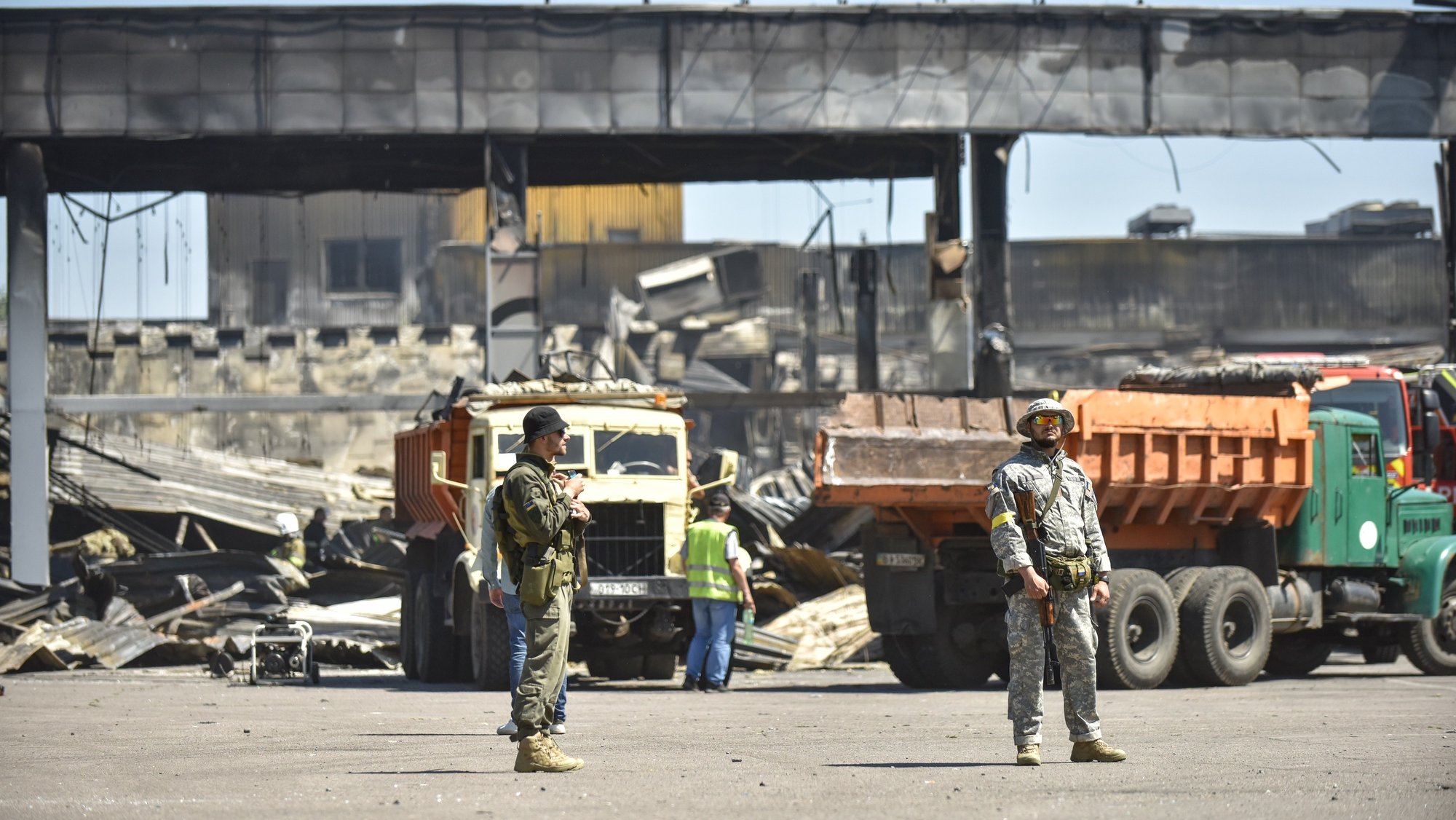 epa10038190 Ukrainian servicemen stand guard near the remains of the destroyed Amstor shopping mall in Kremenchuk, Ukraine, 28 June 2022. At least 18 people died following Russian airstrikes on the crowded shopping mall, the State Emergency Service (SES) of Ukraine said in a Telegram post. The Amstor shopping center one-story building was hit by Russian rockets on 27 June afternoon.  EPA/OLEG PETRASYUK