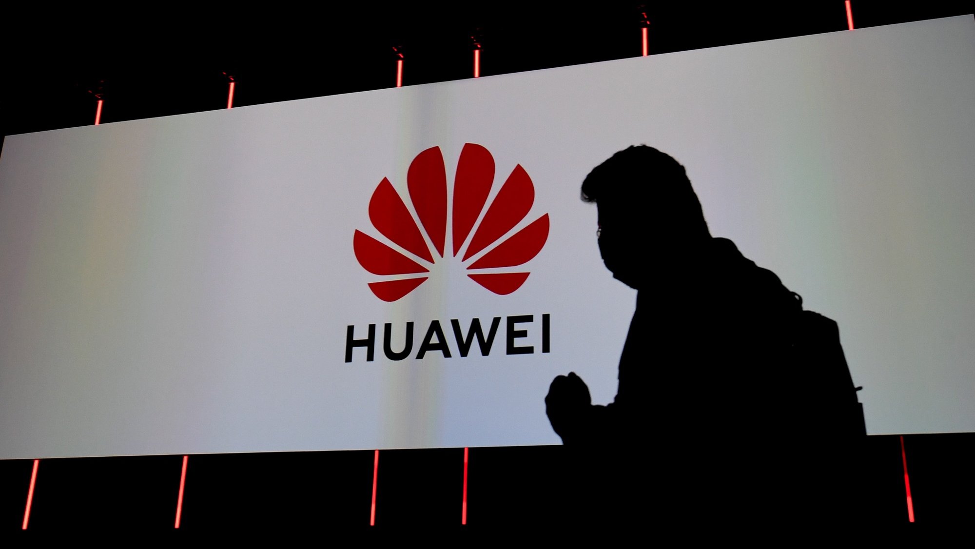 epa08643887 Silhouette of visitor next to the logo of Huawei displayed on a screen at the Huawei stand at the International Consumer Electronics Fair (IFA) in Berlin, Germany, 03 September 2020. The IFA. the world&#039;s leading trade show for consumer electronics and home appliances. runs from 03 to 06 September 2020.  EPA/FILIP SINGER