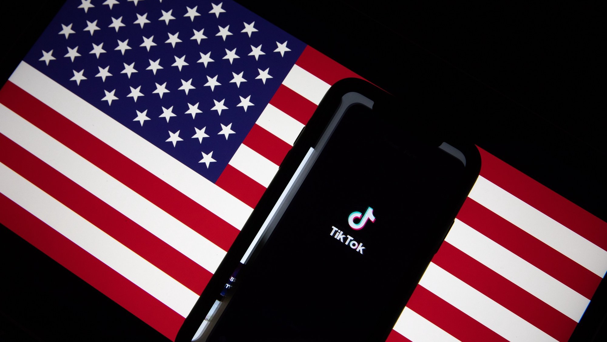 epa08685859 A generic illustration shows the logo of Chinese internet media app TikTok on a phone, and the US flag on a laptop screen, in Beijing, China, 21 September 2020. Chinese-owned mobile app WeChat was set to stop operation in the U.S. on midnight 20 September 2020.  EPA/ROMAN PILIPEY