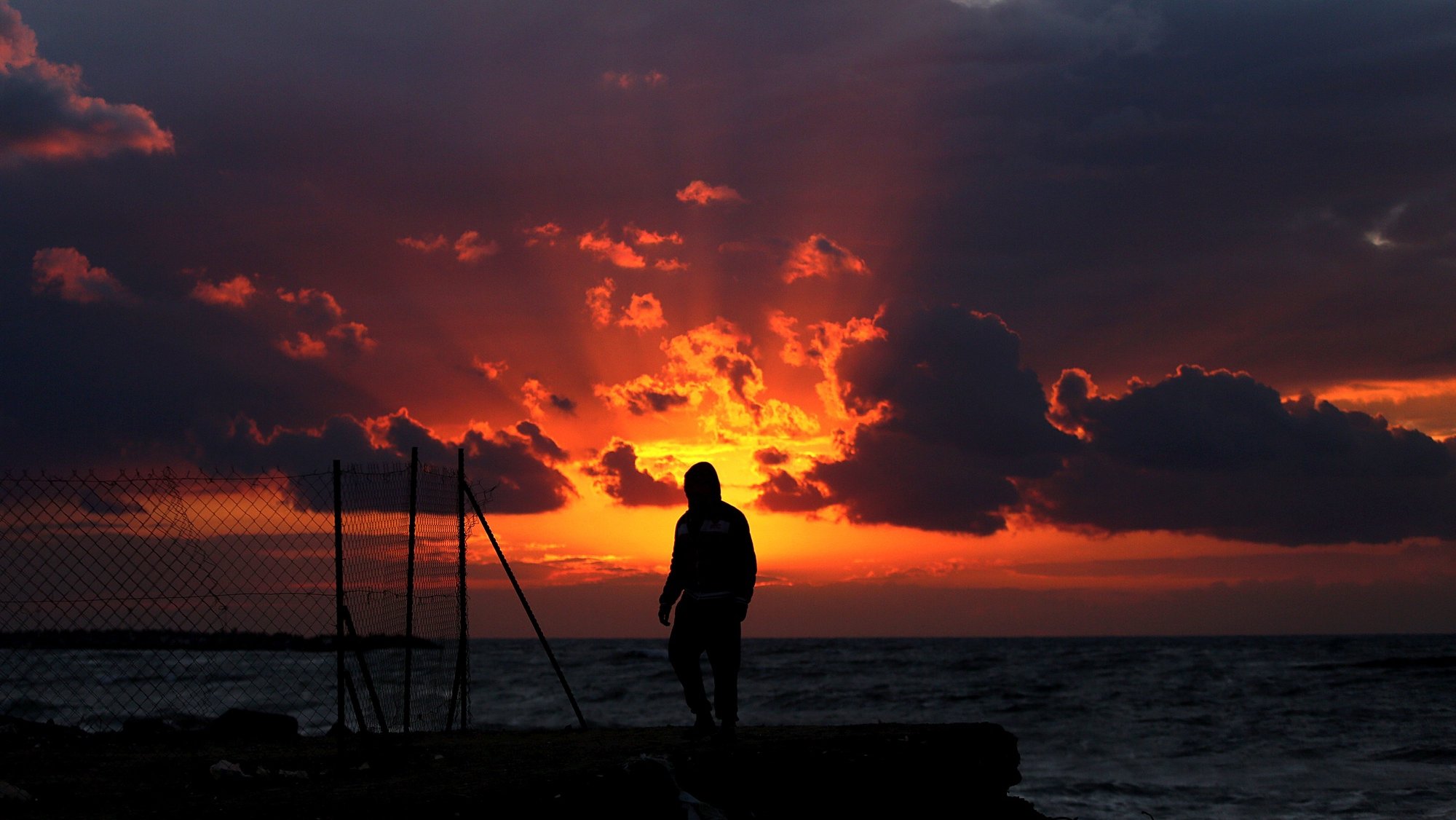 epa05794129 A Palestinian youth enjoys the sunset near the Al Shatea-a refugee camp during cold weather in Gaza City, Gaza Strip, 14 February 2017.  EPA/MOHAMMED SABER