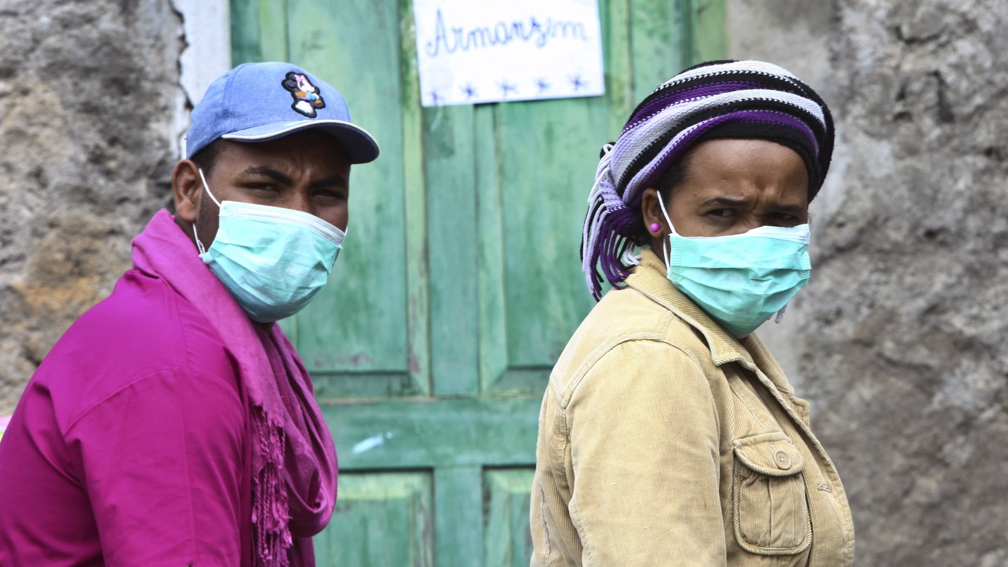 Um homem e uma mulher protegem-se com máscaras no centro de acolhimento da Achada Furna onde a população da Portela afetada pelo vulcão aguarda o regresso às suas casas, Achada Furna, Cabo Verde,  29 de novembro de 2014. JOÃO RELVAS/LUSA