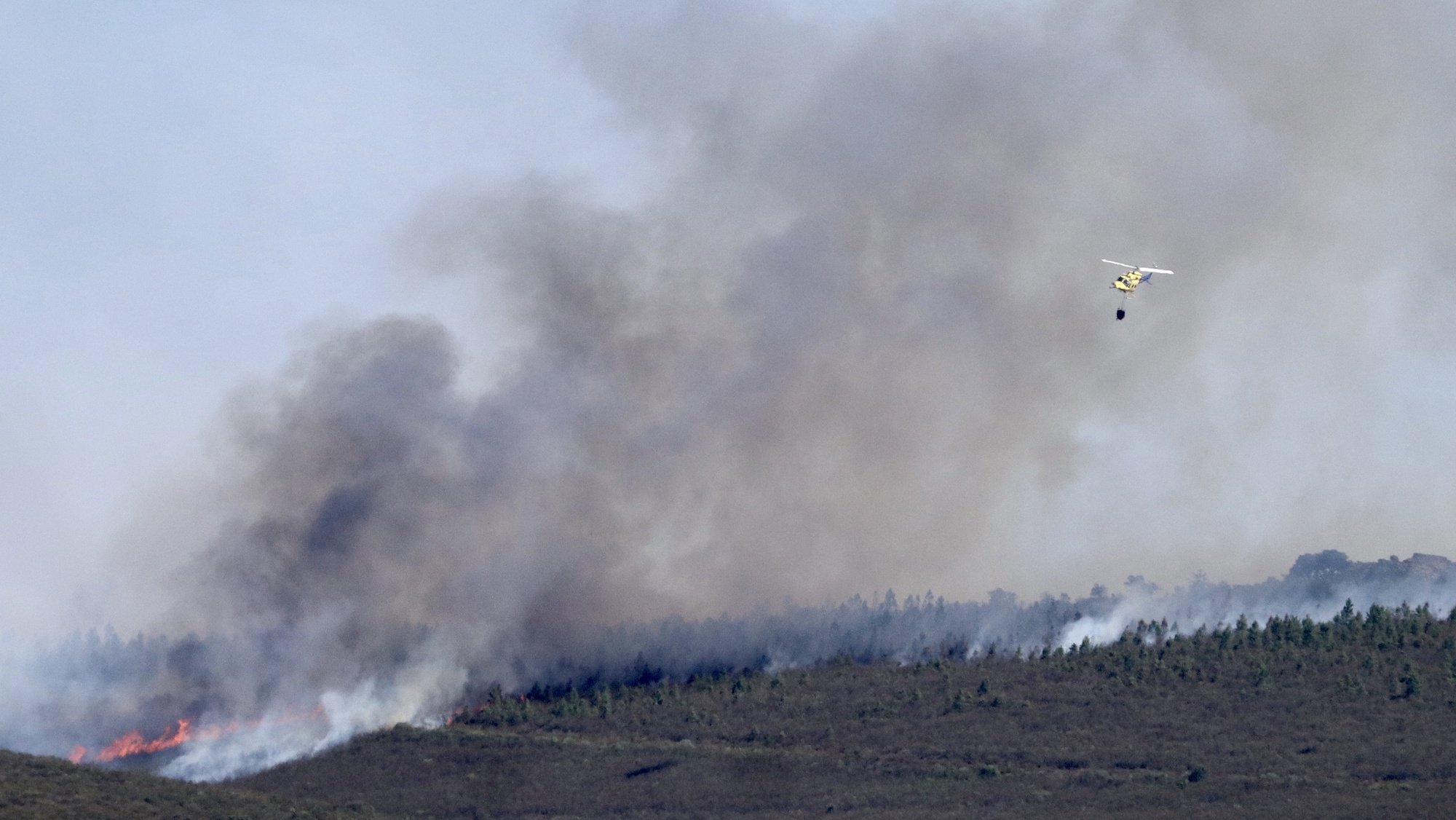 epa10079617 A firefighting helicopter flies over a forest fire in Losacio, province of Zamora, Spain, 19 July 2022. The fire forced the evacuation of some 34 towns and forced the closing of the AVE high-speed train line.  EPA/MARIAM A. MONTESINOS