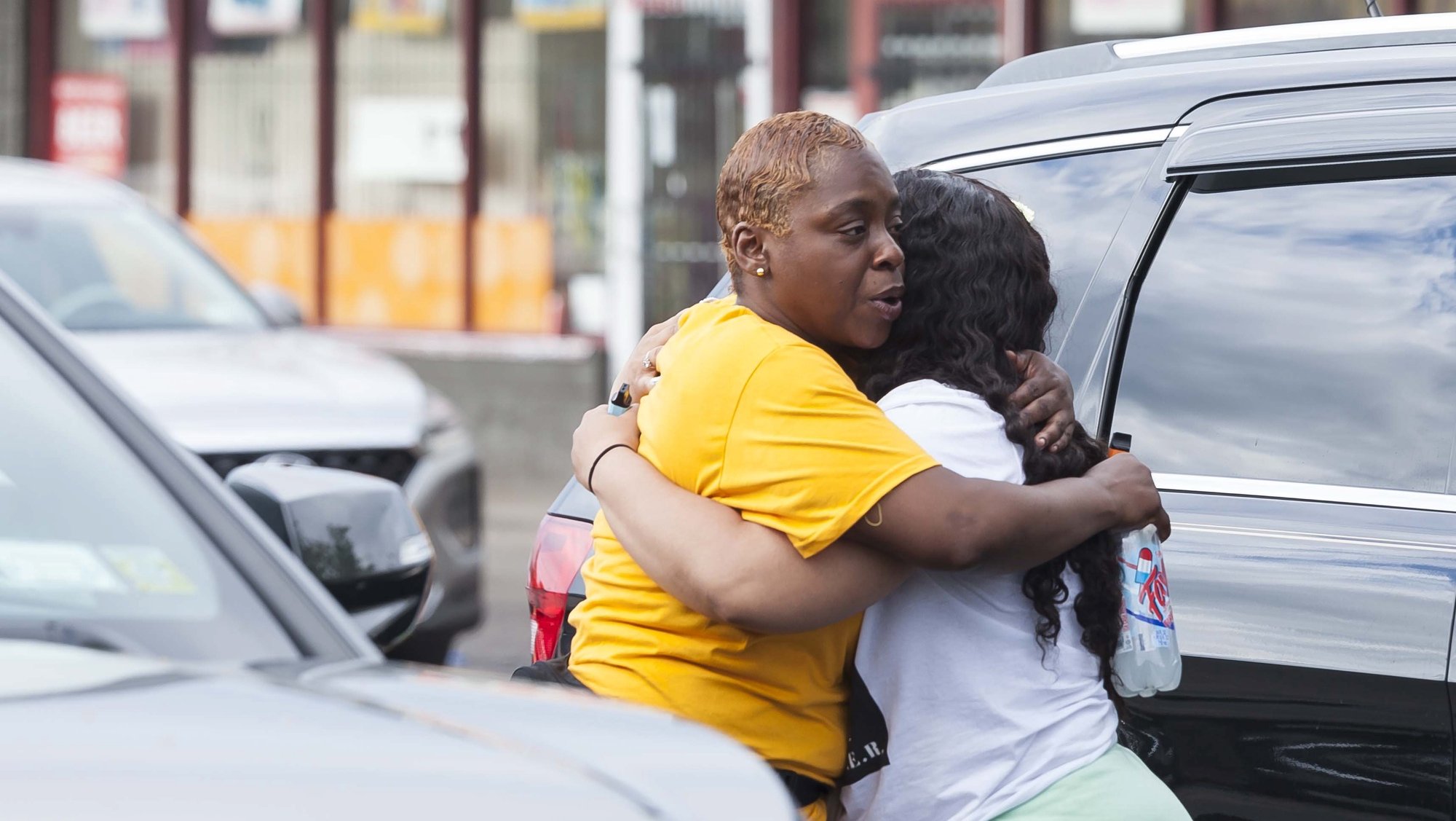 epa09947829 Two people hug near the scene of a mass shooting at the Tops Friendly Market grocery store in Buffalo, New York, USA, 14 May 2022. A gunman, who has been taken into custody by police, reportedly opened fire at the market killing as many as 10 people.  EPA/BRANDON WATSON
