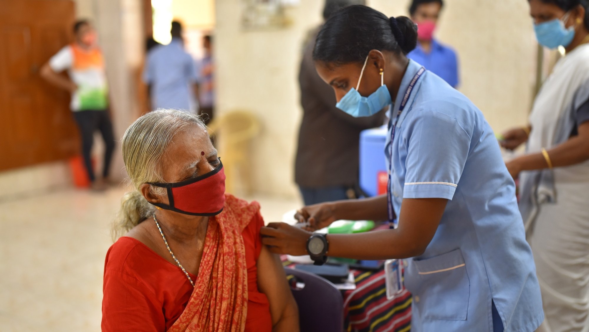 epa09282817 A woman receives a dose of Covid-19 vaccine as others wait to getÂ inoculated, at the Chennai Middle School, in Chennai, India, 18 June 2021. With coronavirus disease (COVID-19) cases dropping in India, the Tamil Nadu government also announced various relaxations against the ongoing lockdown.  EPA/IDREES MOHAMMED