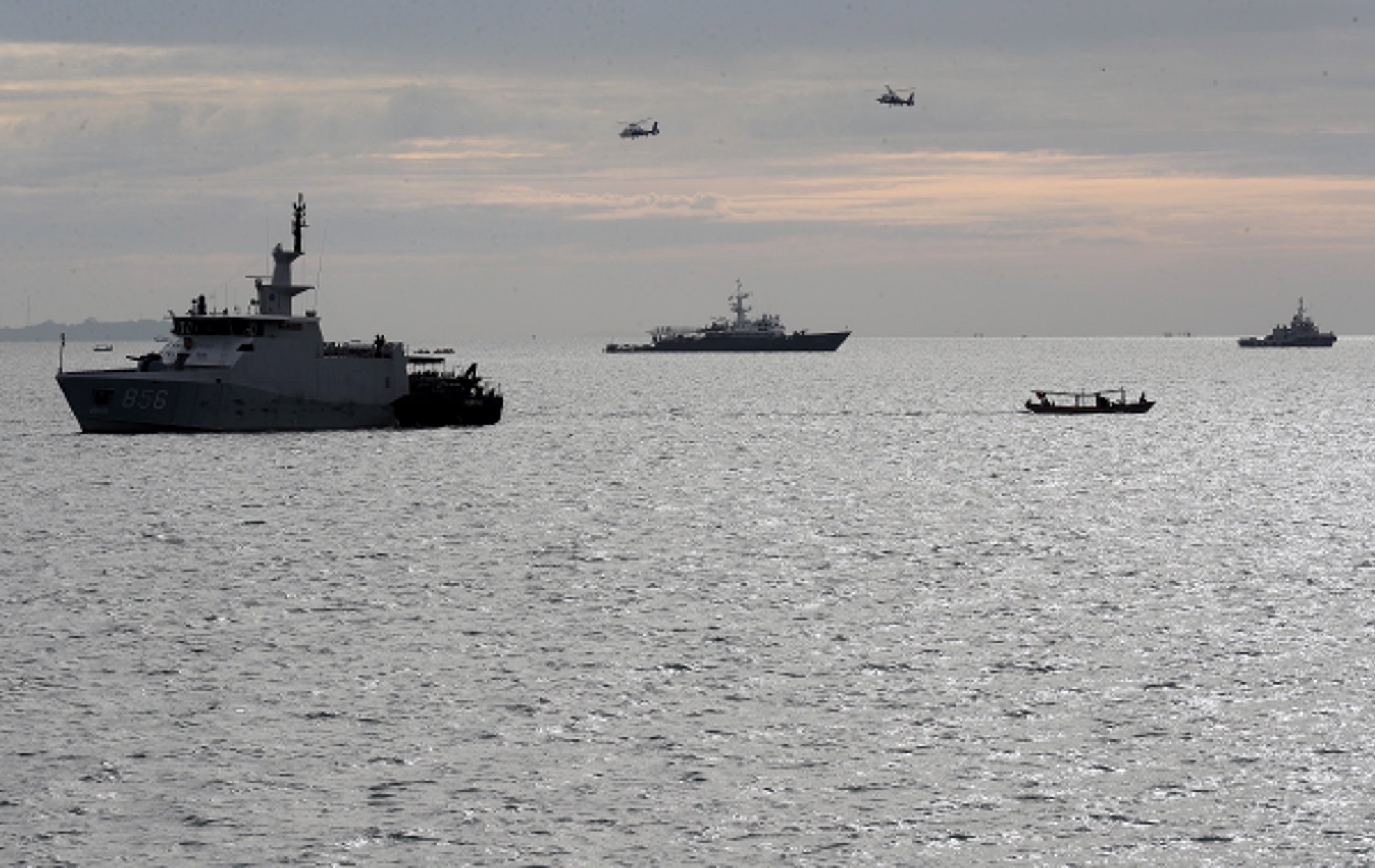 epa08929639 Helicopters and Navy ships are seem during a search and rescue operation near the suspected crash site of Sriwijaya Air flight SJ182 in the waters off Jakarta, Indonesia, 10 January 2021. Contact to Sriwijaya Air flight SJ182 was lost on 09 January 2021 shortly after the aircraft took off from Jakarta International Airport while en route to Pontianak in West Kalimantan province.  EPA/Bagus Indahono
