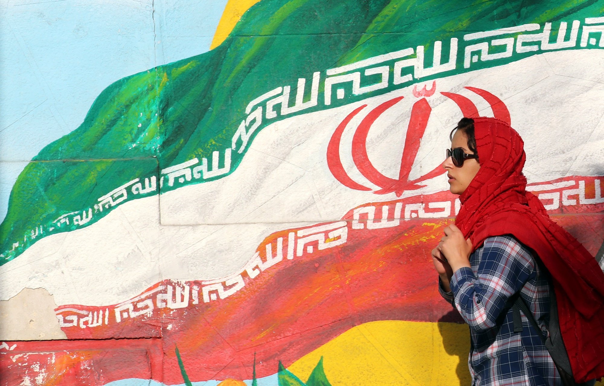 epa09992137 An Iranian walks next to a wall painting of Iran’s national flag at a street in Tehran, Iran, 02 June 2022. The Iranian Health Ministry announced zero death toll from COVID-19 for the first time since the beginning of the pandemic.  EPA/ABEDIN TAHERKENAREH