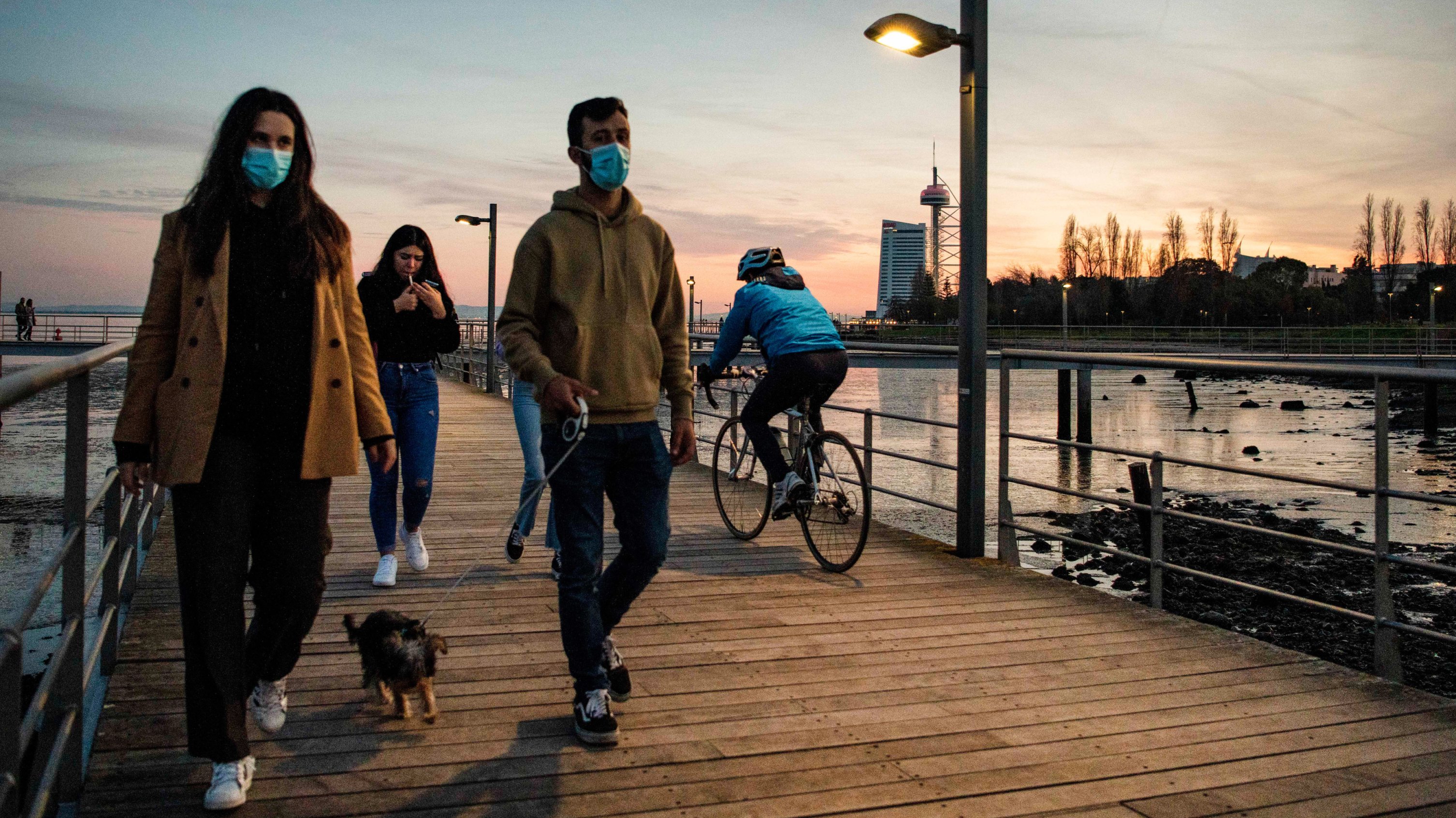 People wearing face masks are seen walking along the Tagus