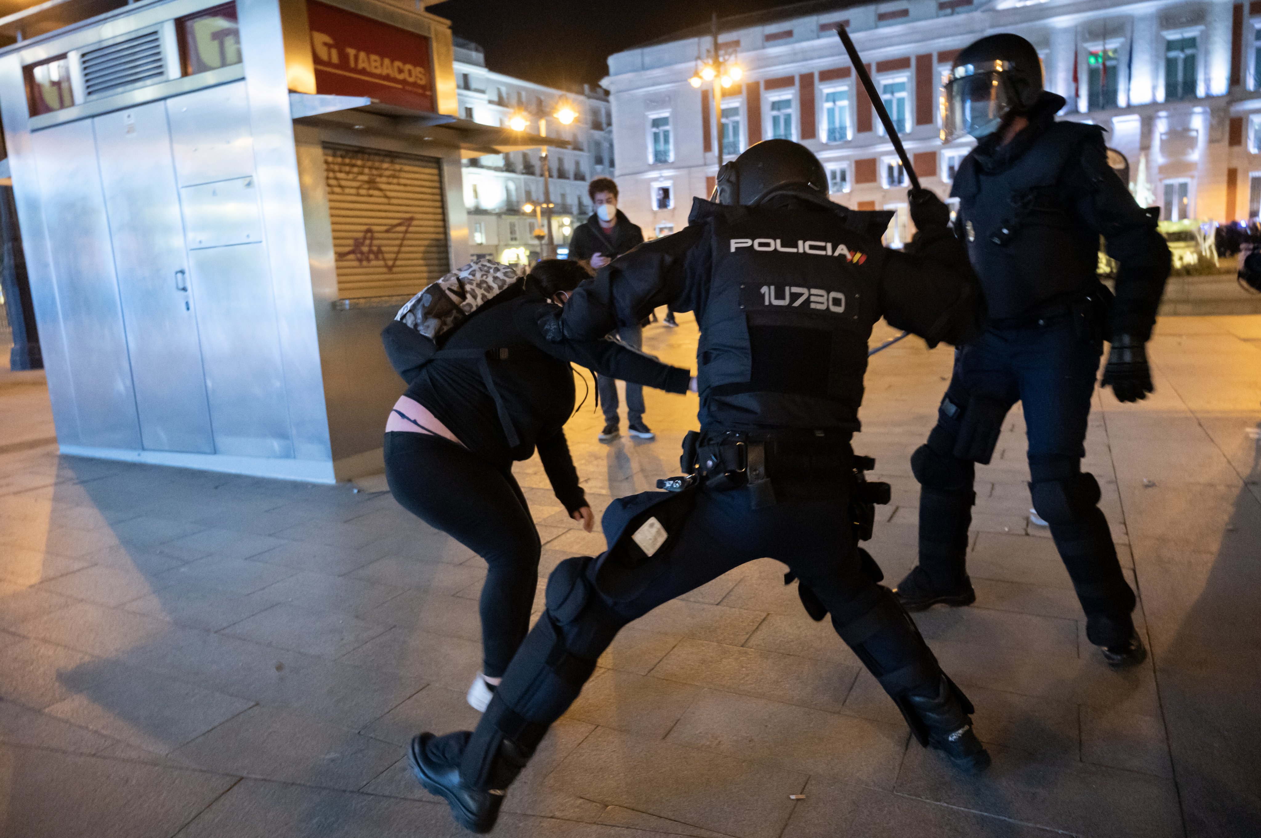 Riot police beating a woman during clashes in a