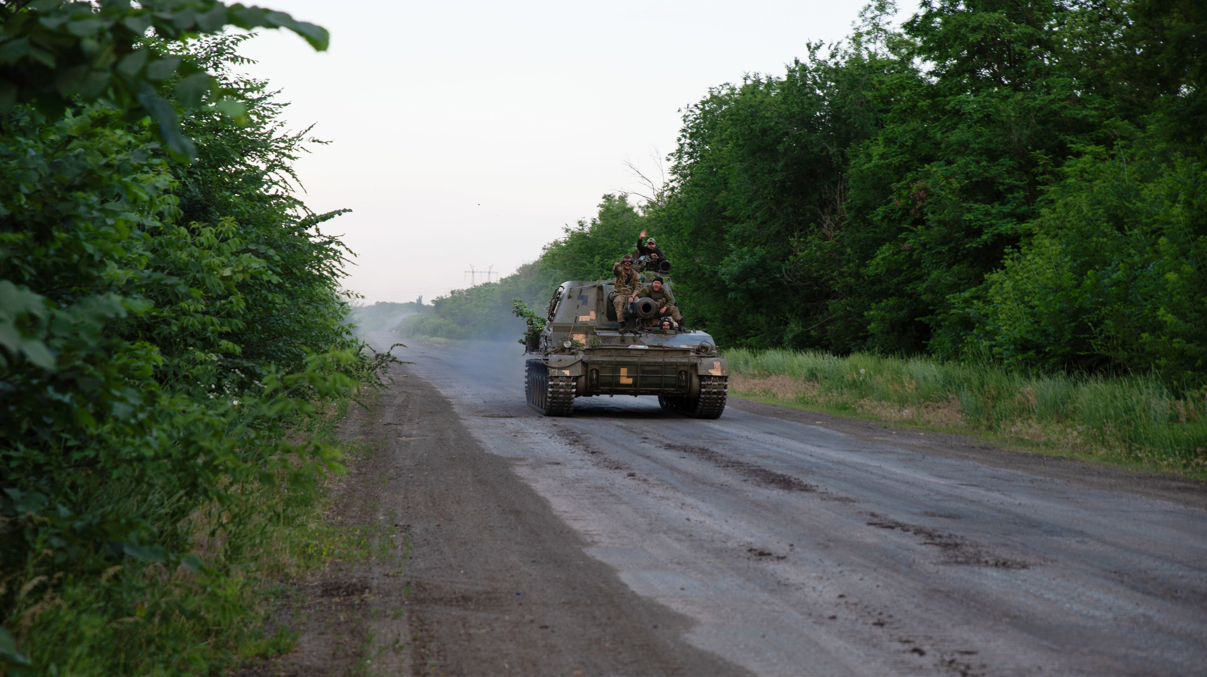 Ukrainian soldiers ride on an armored vehicle outside