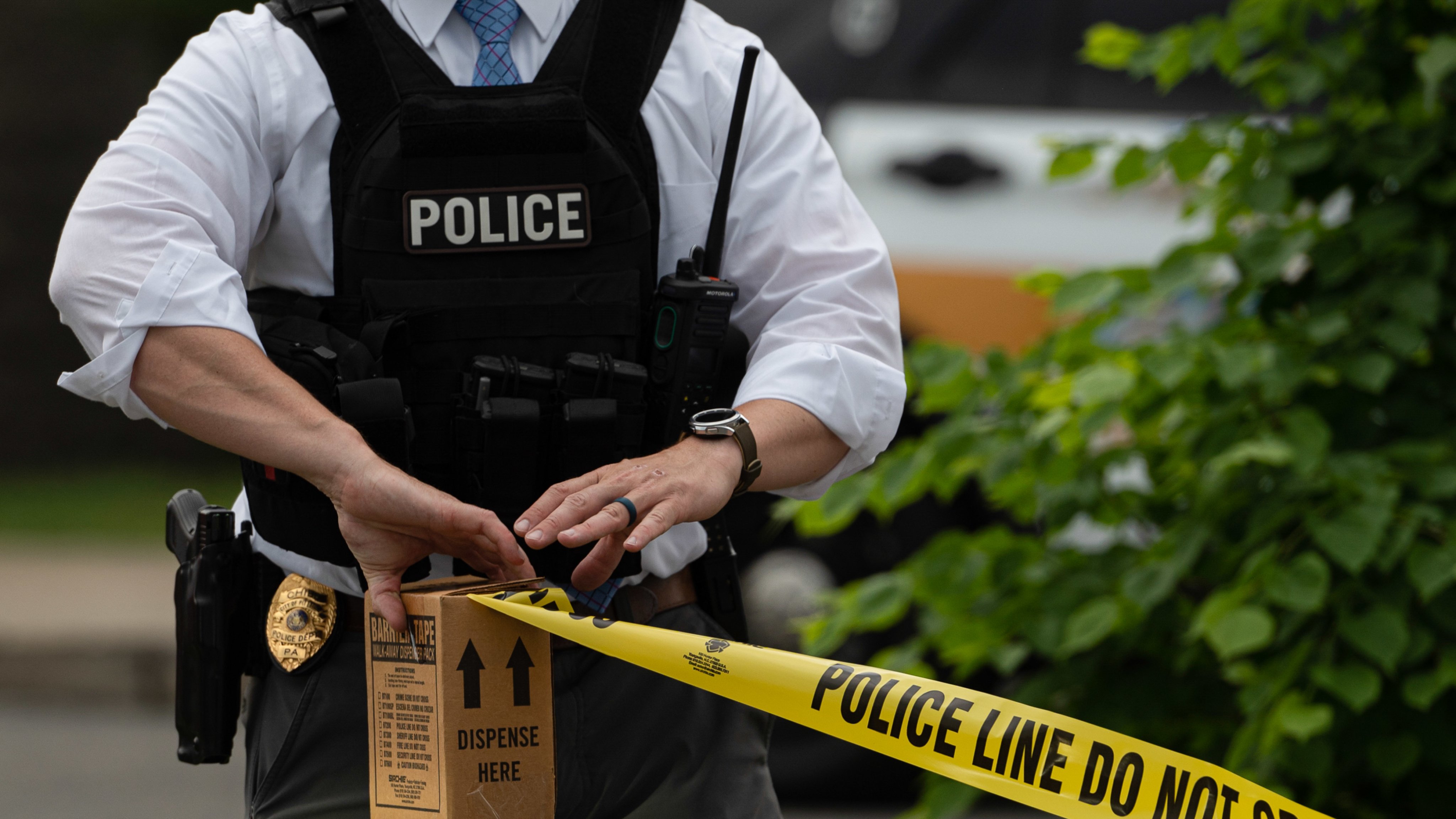 A police officer pulls police tape after a shooting in a