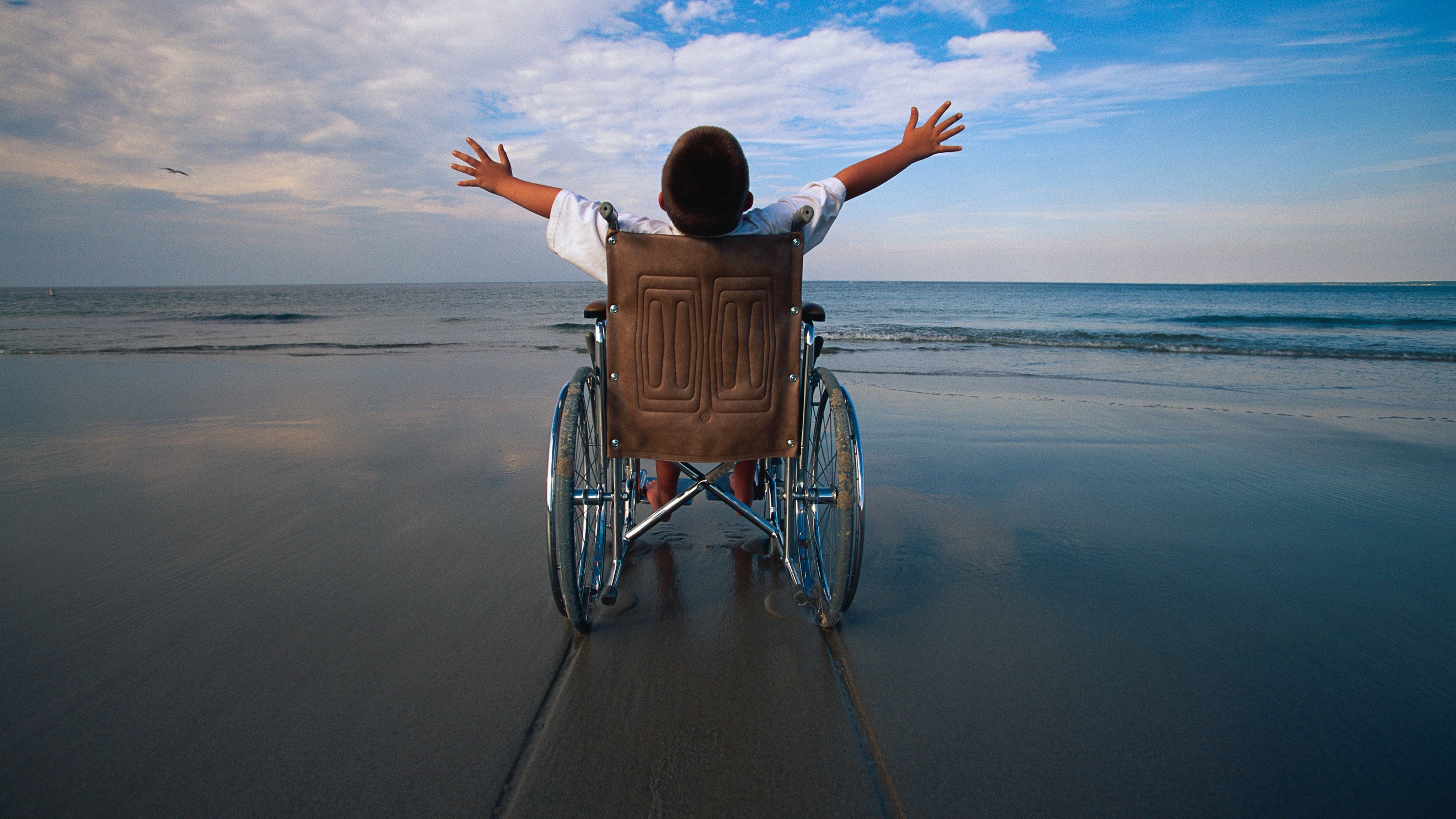 Rapaz numa cadeira de rodas na praia