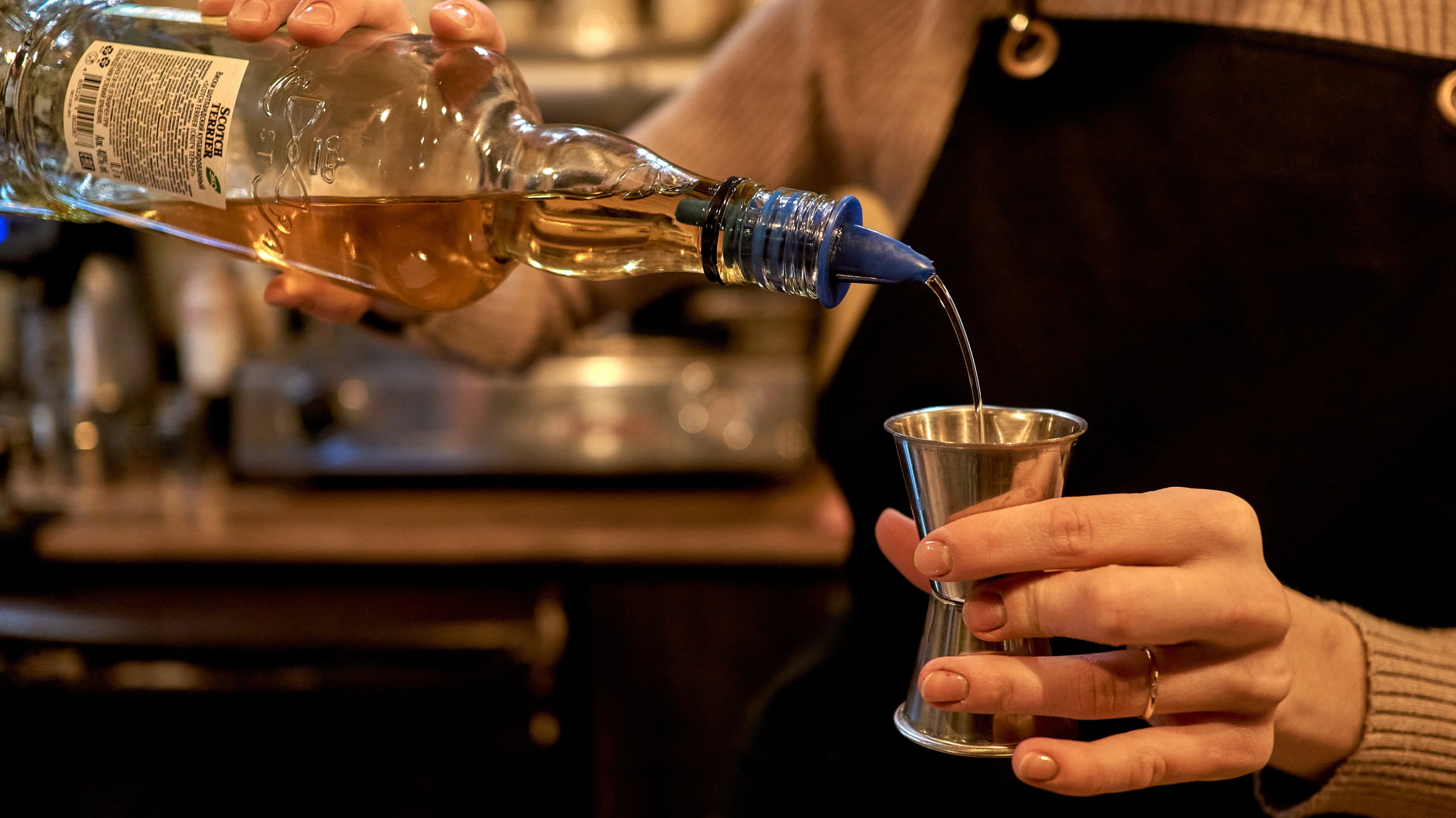 A barmaid pours whiskey at a Tolkien-themed city cafe on