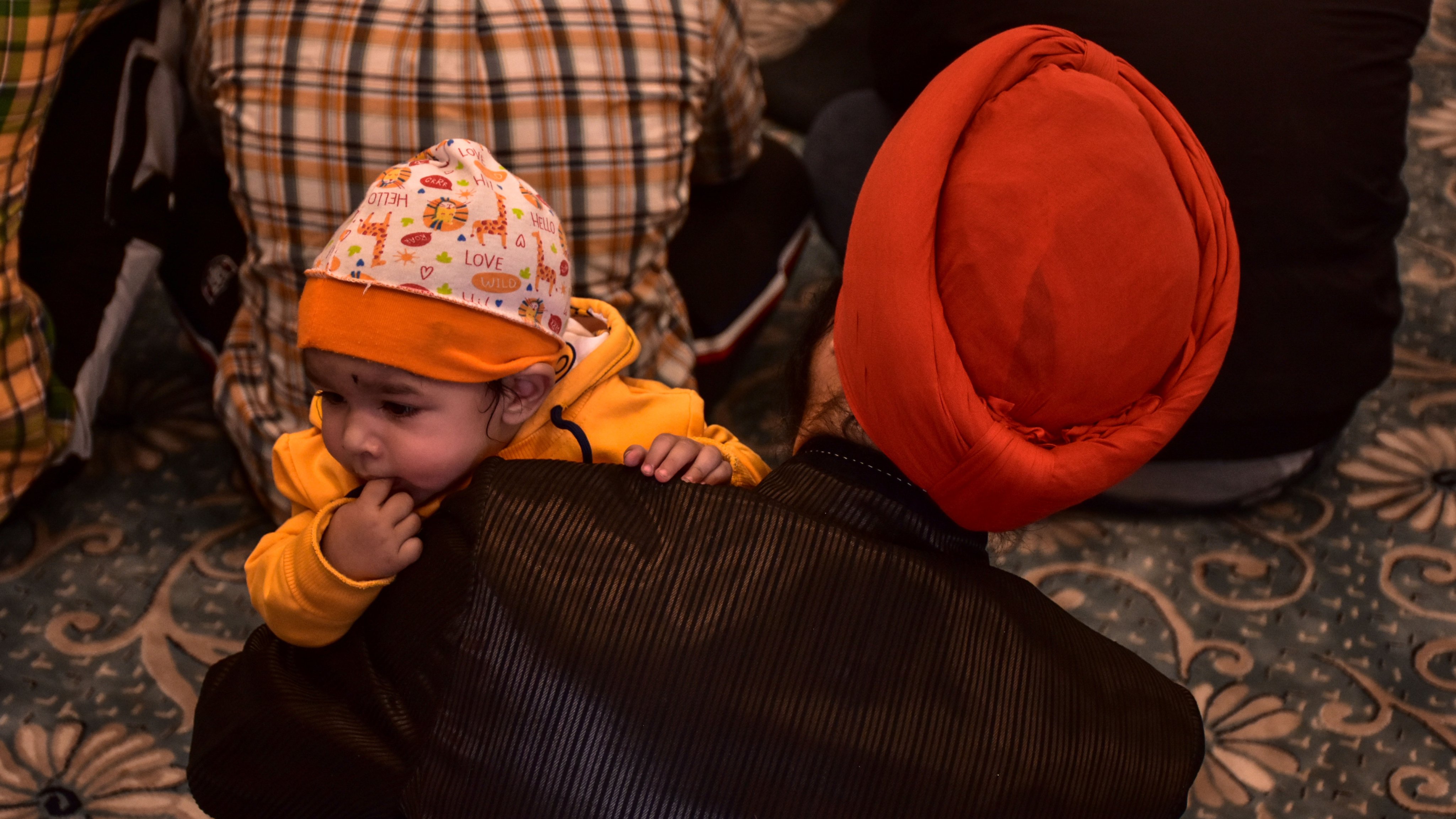 A Sikh devotee holds his baby during rituals inside a